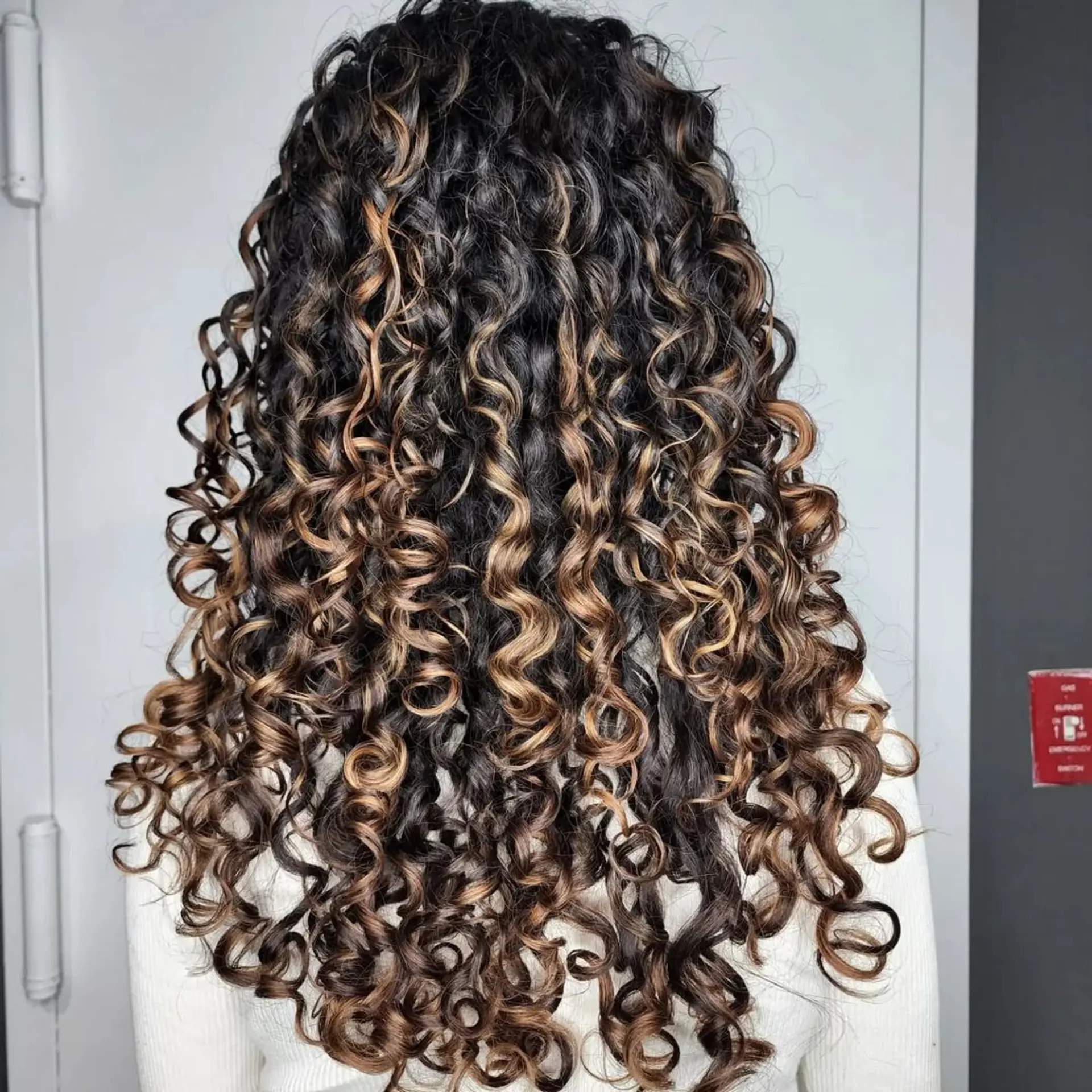 Long, curly hair with a gradient balayage effect from black to brown to blonde, featuring voluminous, defined curls with a healthy shine. 1
