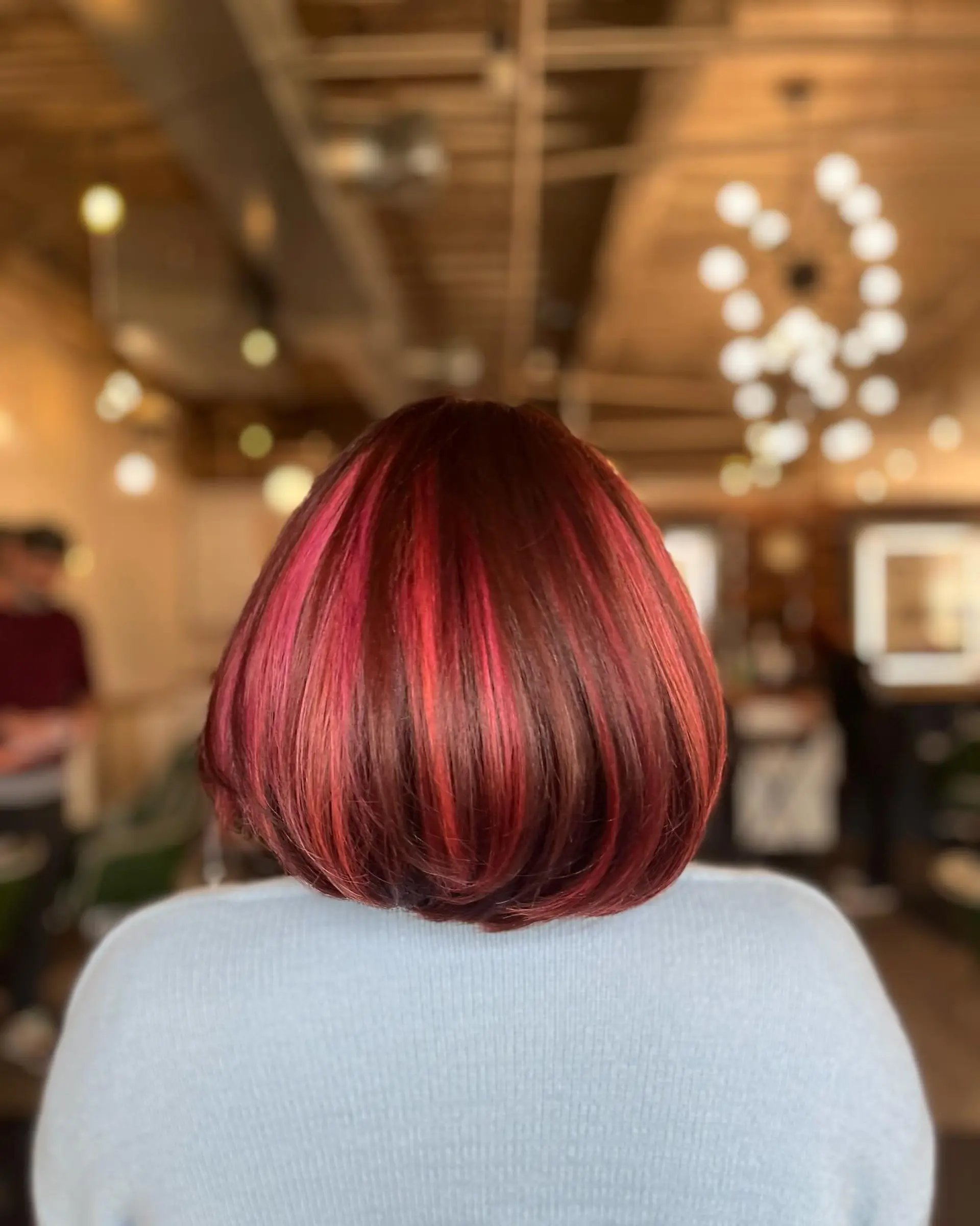 A rounded short bob styled smooth with vibrant pink and magenta highlights over a rich auburn base. 1