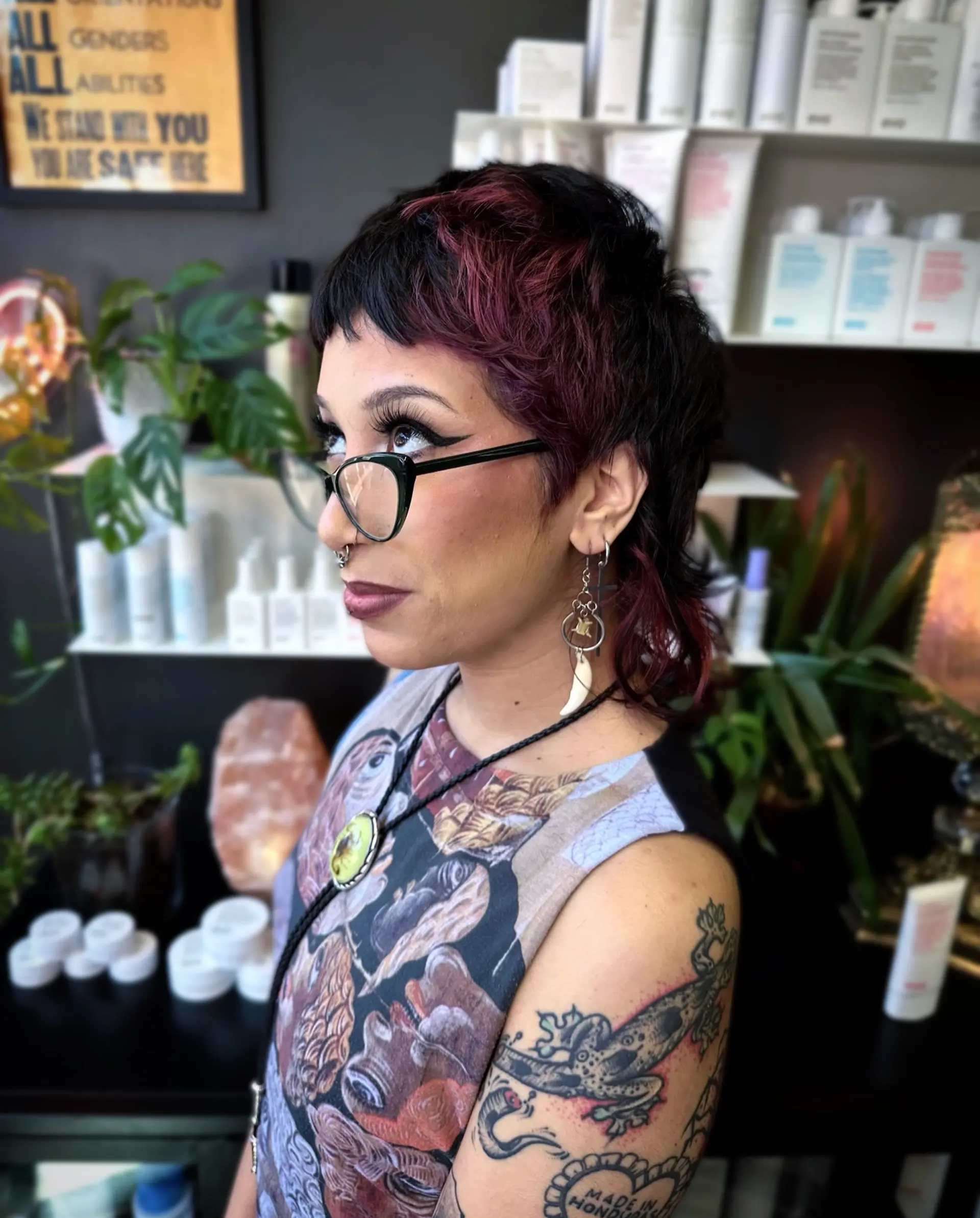 A textured modern mullet featuring micro baby bangs and rich burgundy highlights woven into dark hair. 1