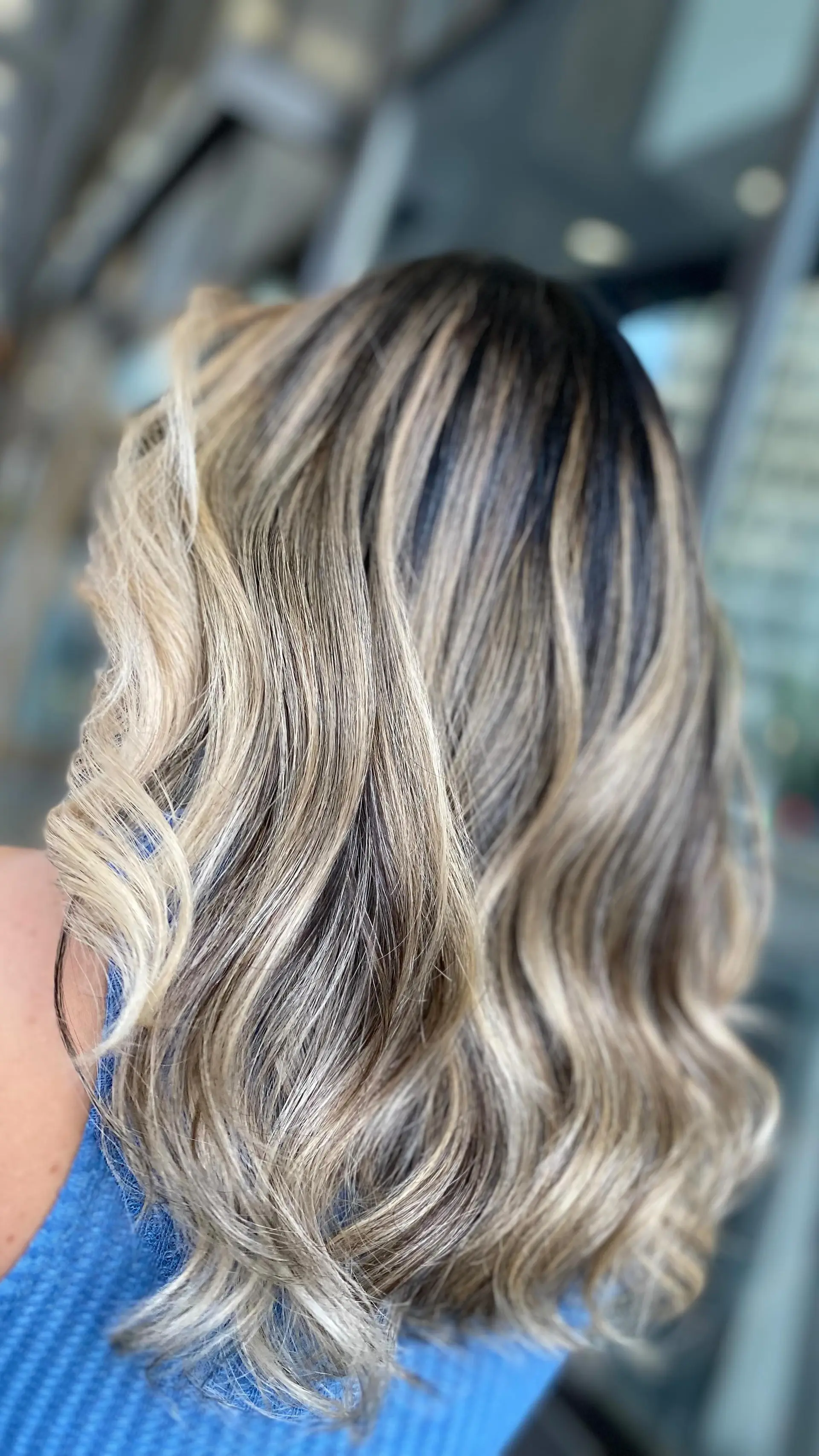 Medium-length wavy hair featuring a seamless dimensional blonde foilayage with a shadowed natural root. 1
