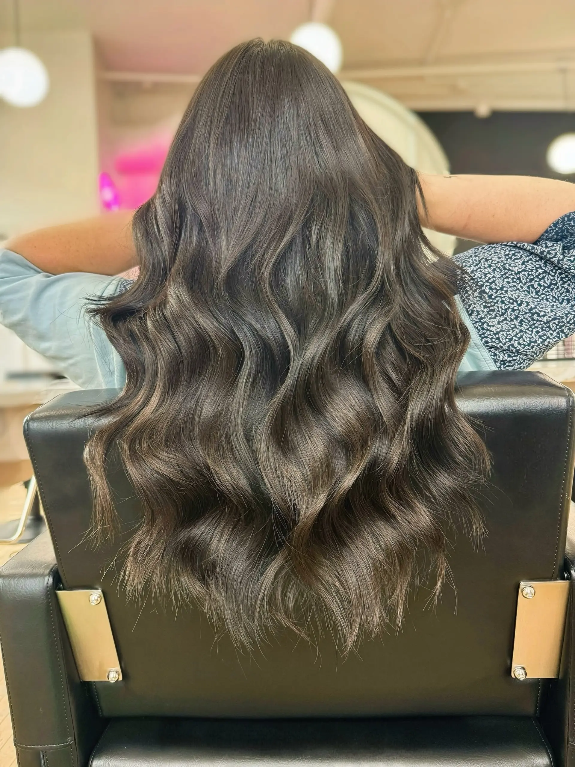 Long dark brunette hair styled into rich, flowing waves with seamless blending and dimensional shine. 1