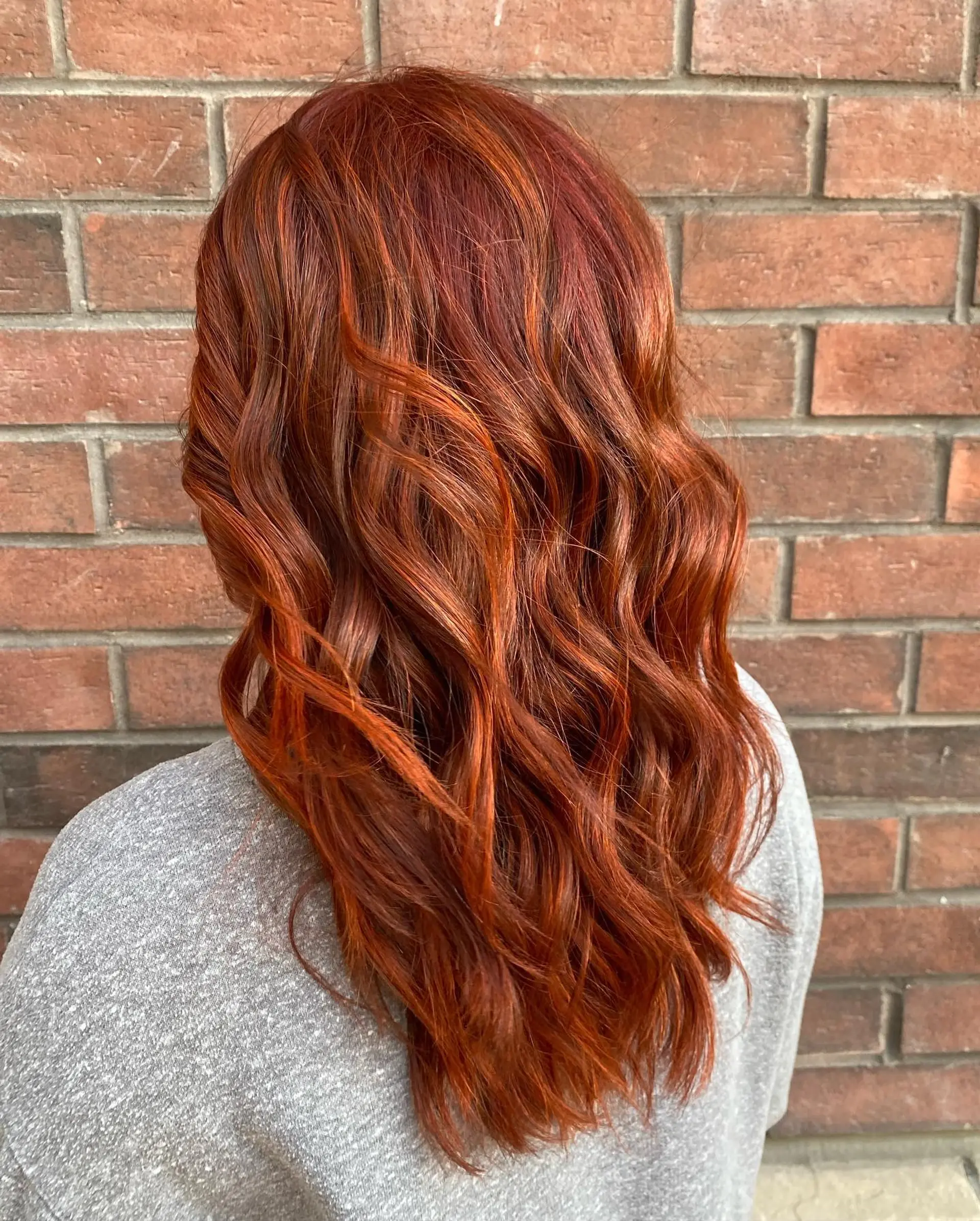 Rich, multi-dimensional copper red hair styled with loose, flowing waves. 1