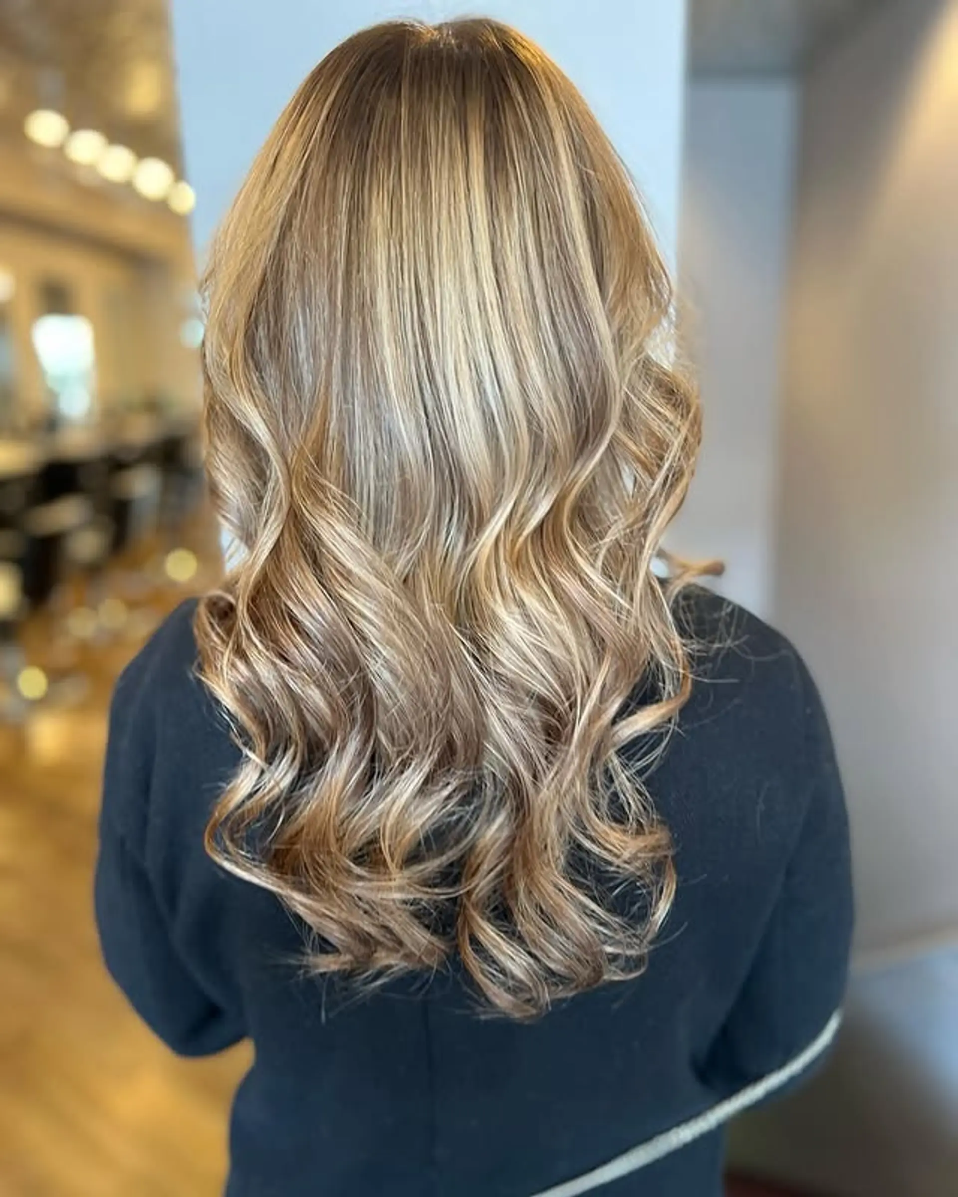 A long, wavy hairstyle featuring a bronde balayage. 1