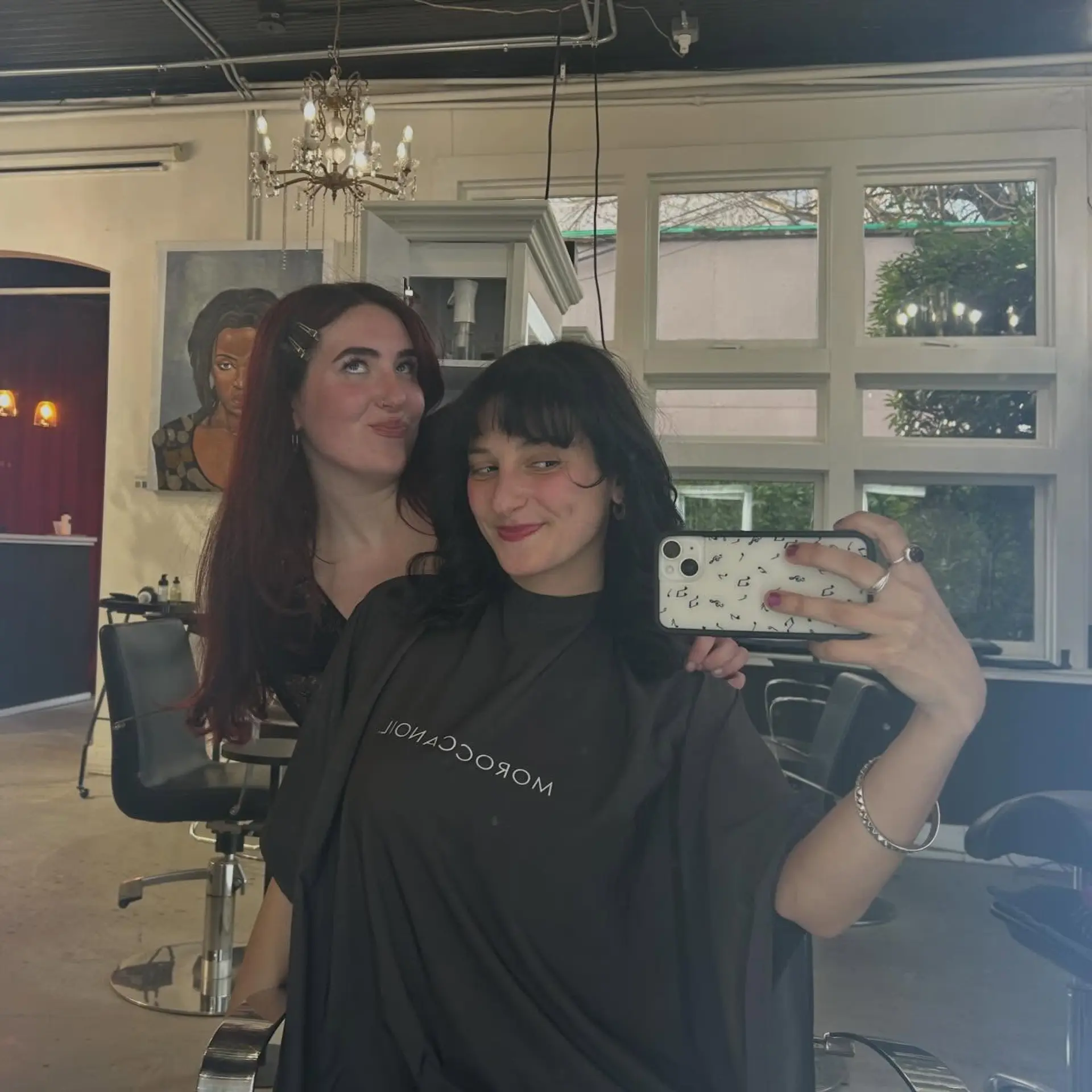 Medium-length dark hair styled with a bouncy, textured blowout and full fringe bangs framing the face. 1