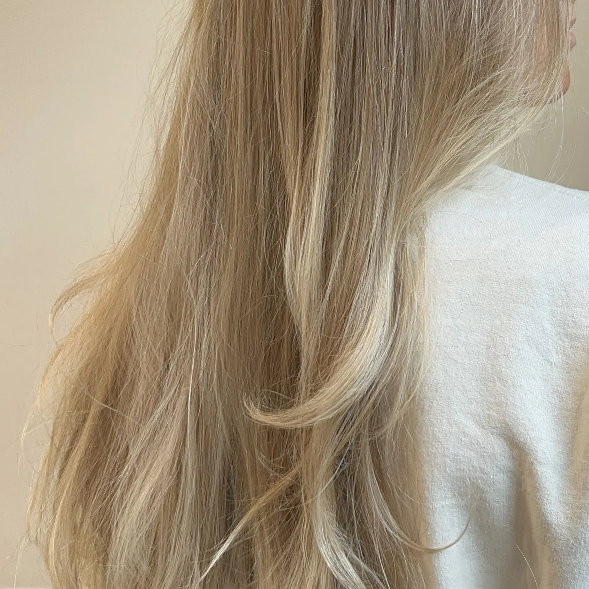 Long, flowing blonde hair styled with soft, natural texture and gentle face-framing layers. 1