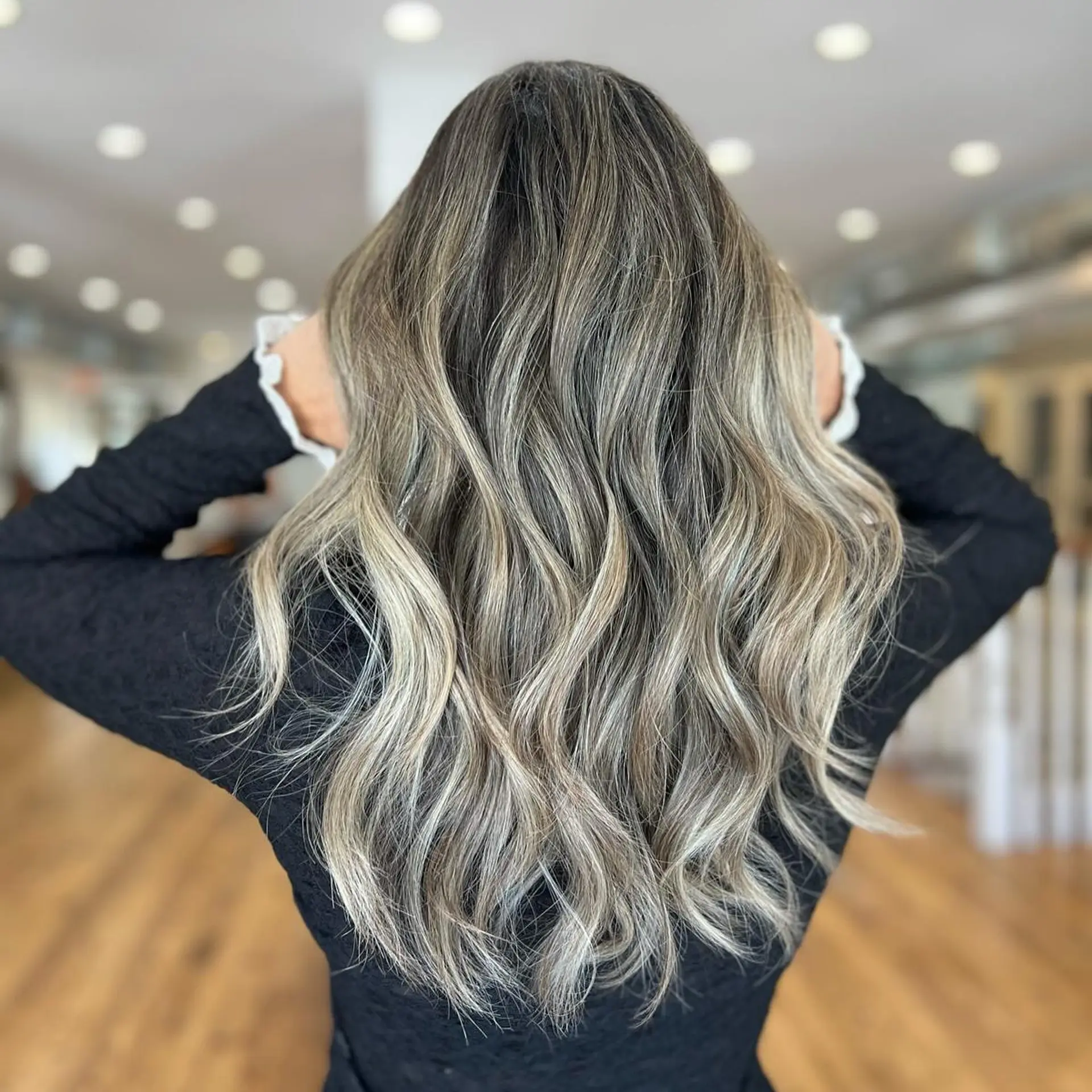 Long wavy hair with an ash blonde balayage, featuring dark roots and beige highlights. 1