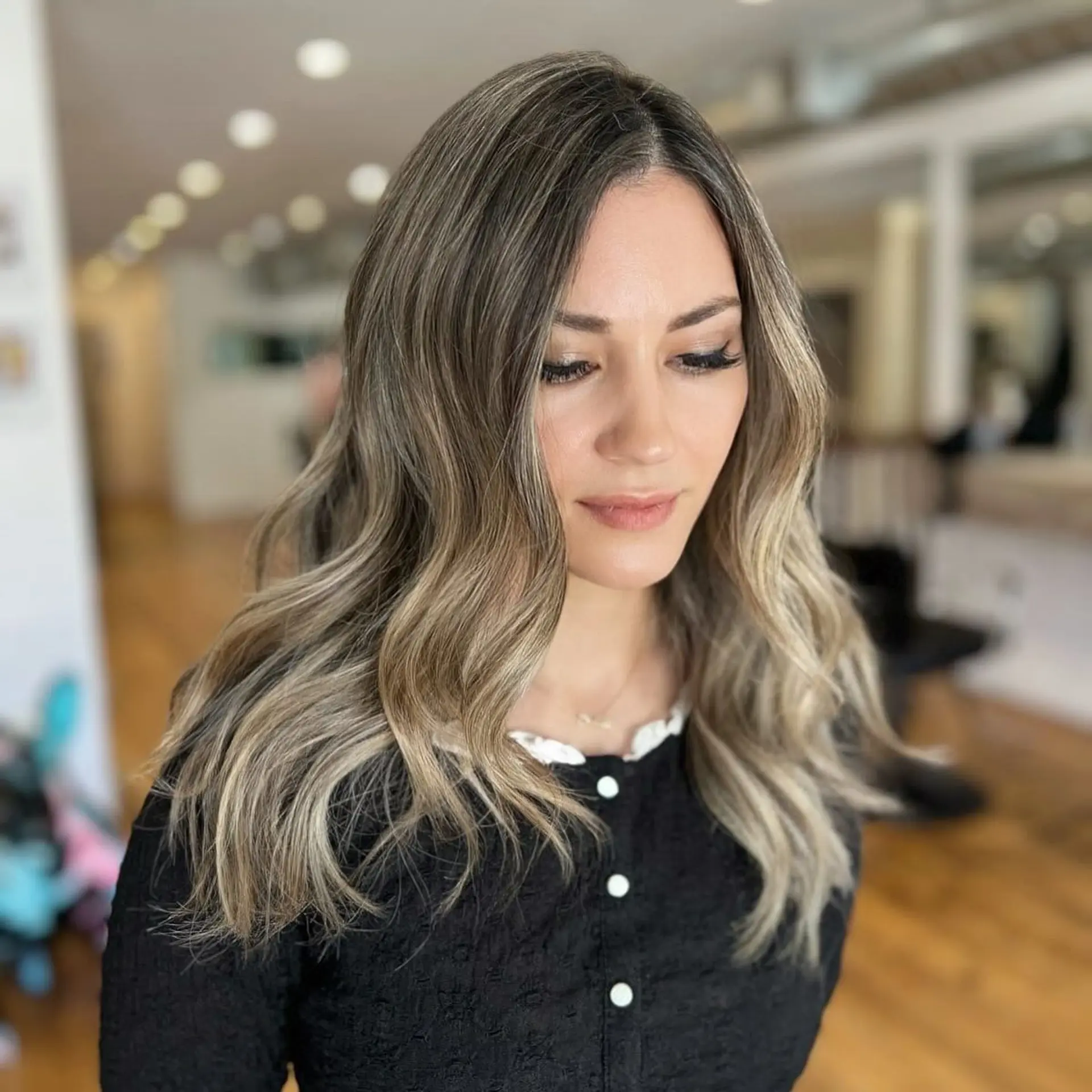 Long wavy hair with an ash blonde balayage, featuring dark roots and beige highlights. 2