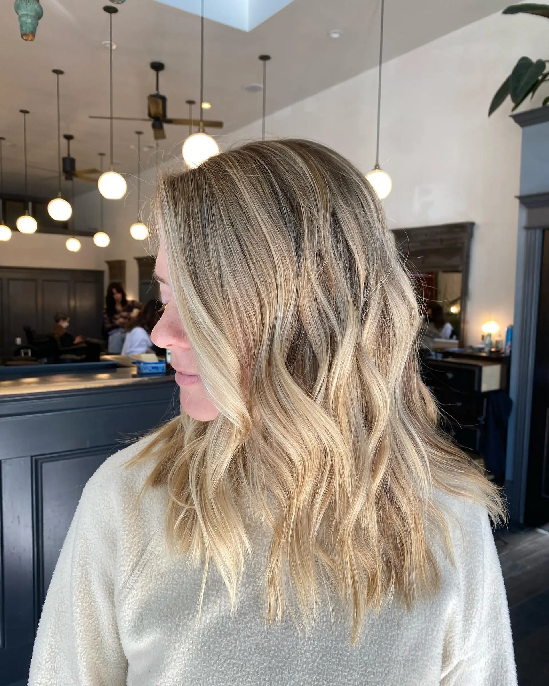 Medium-to-long dimensional blonde hair styled into soft, effortless waves. 1