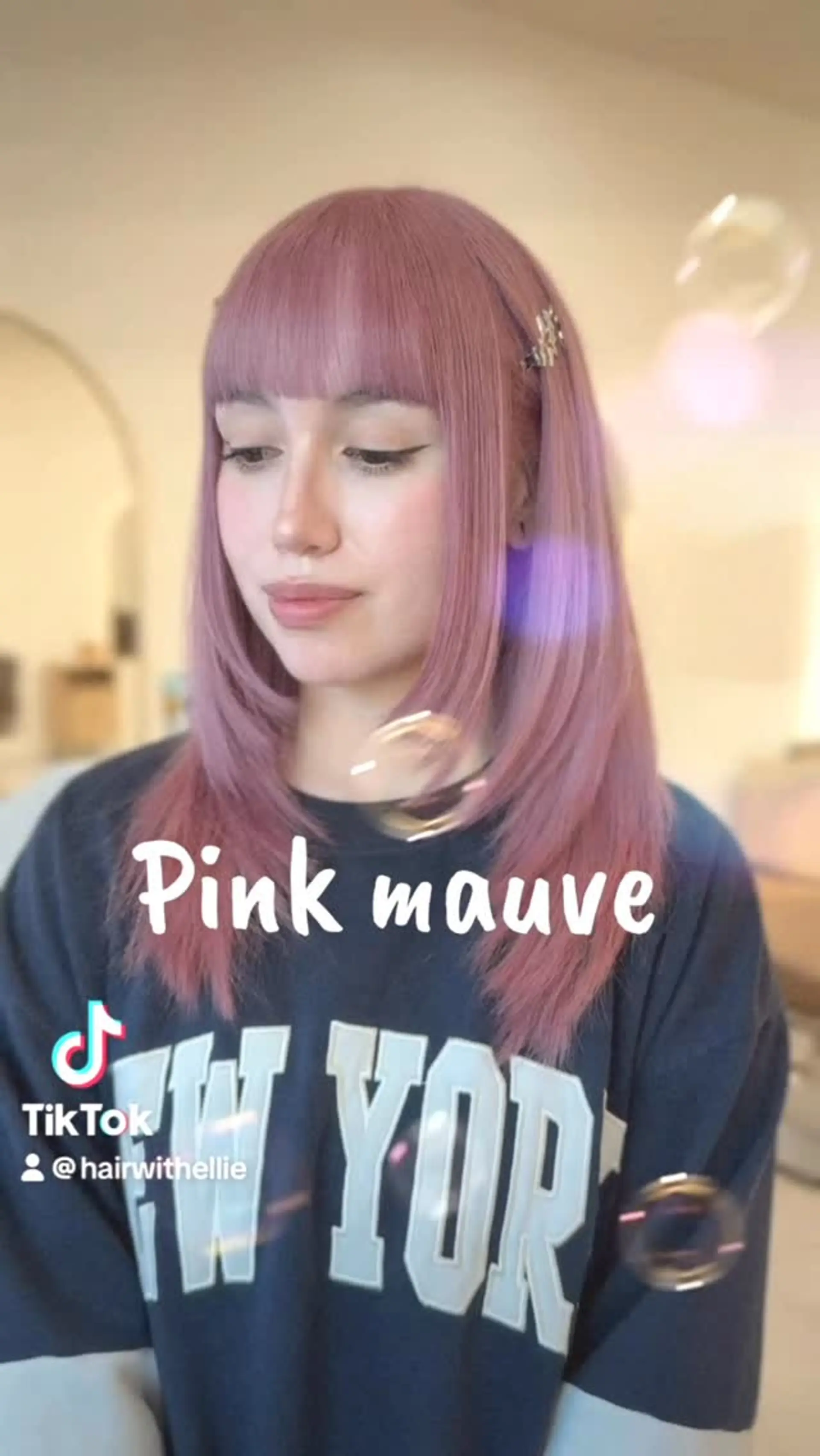 Medium-length straight hair in a soft pink mauve tone, styled with a blunt straight fringe and face-framing front layers. 1