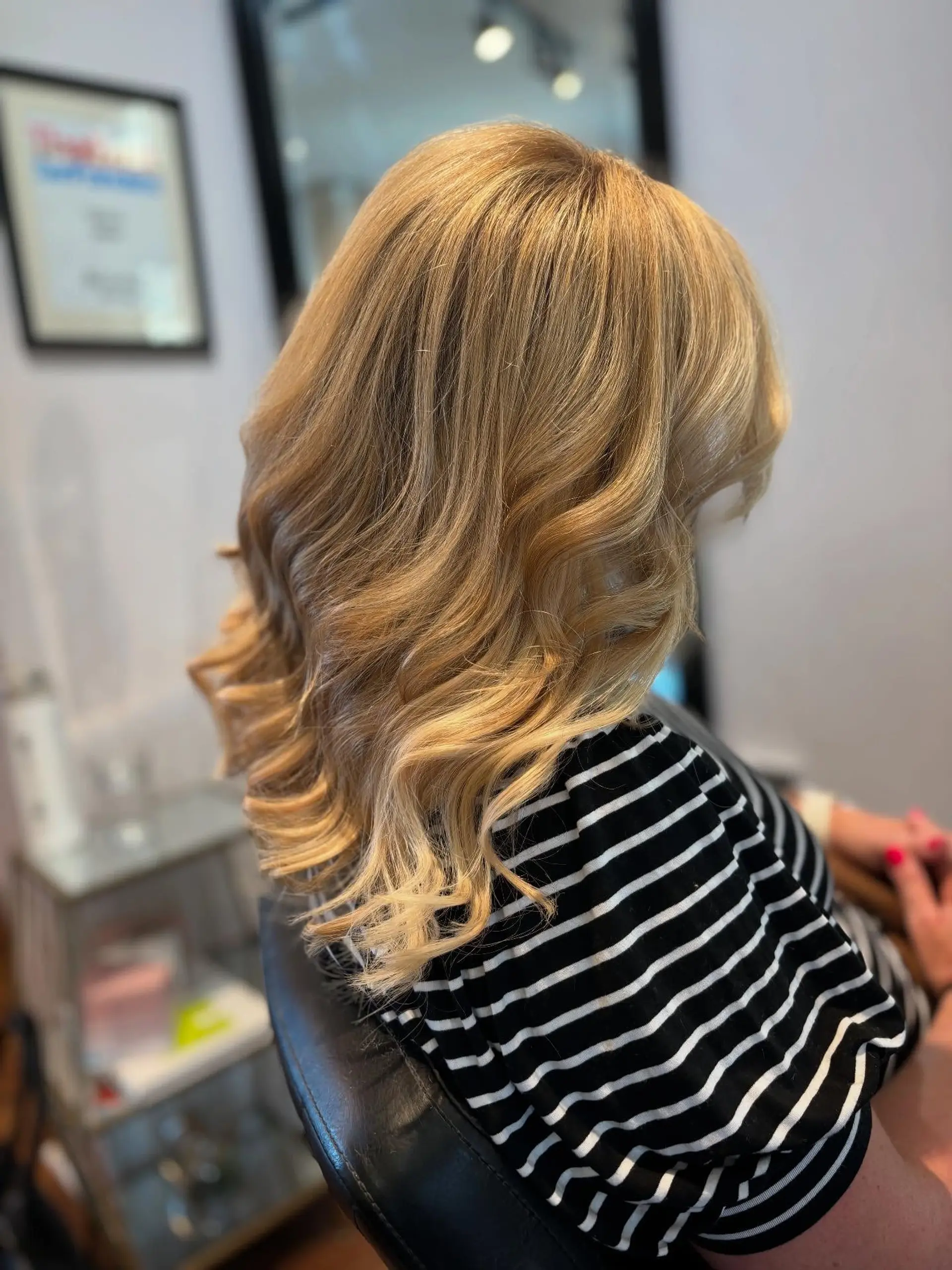 Medium-length warm blonde hair styled in soft, cascading waves with seamless layers. 1