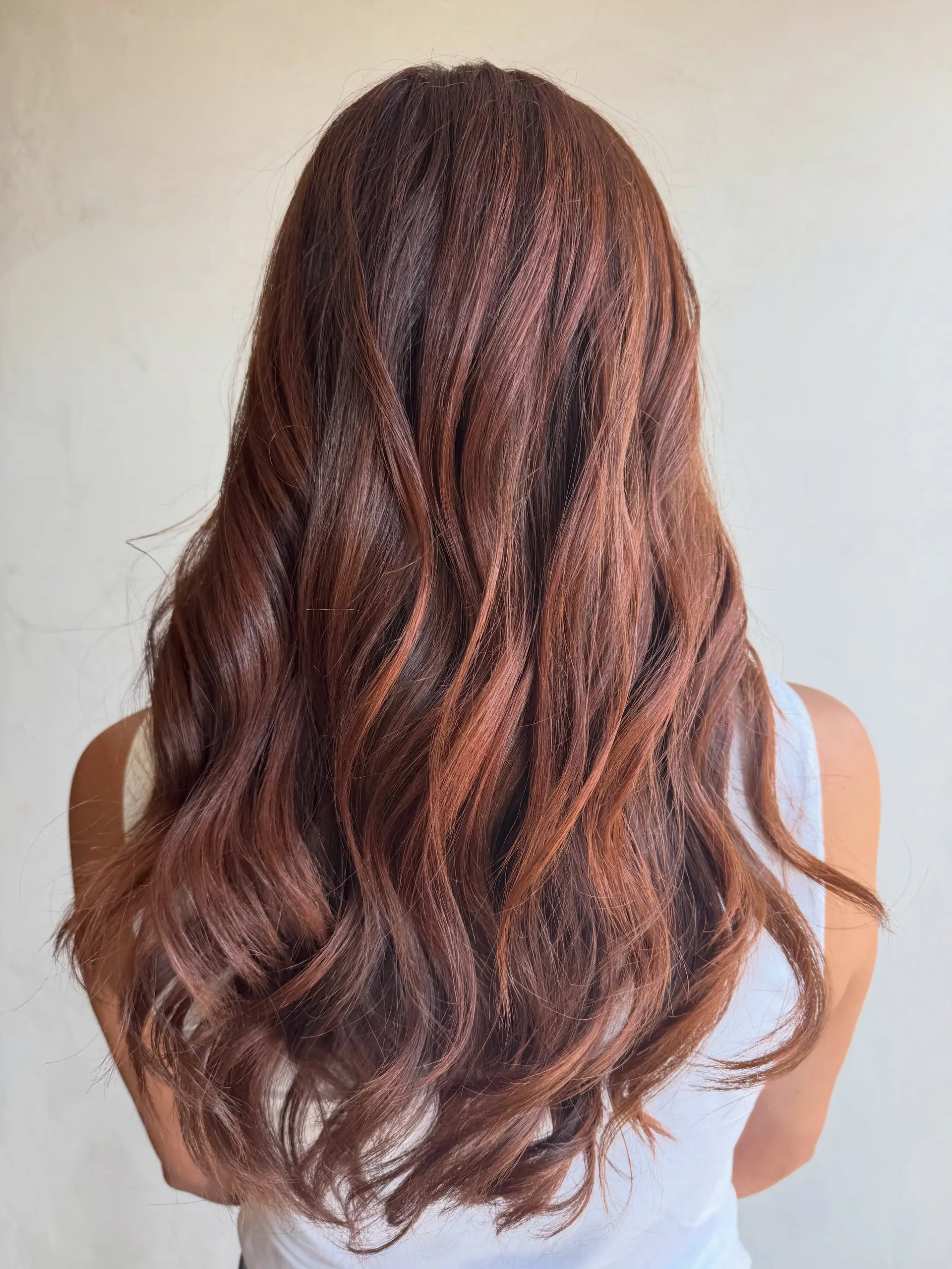 Long, voluminous hair styled in soft, cascading waves with a dimensional cinnamon copper hue. 1