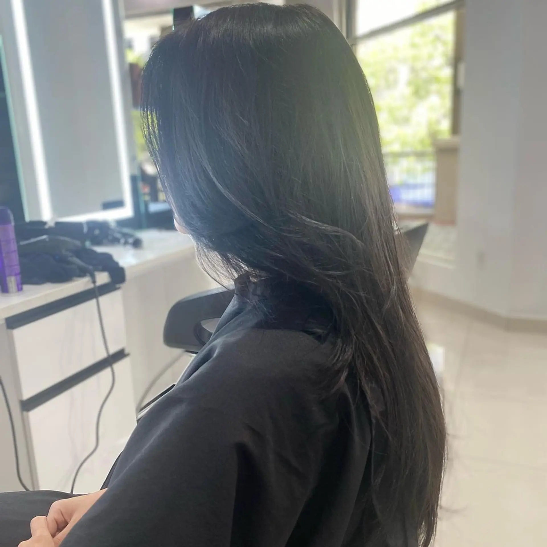 Long, straight black hair with slight waves towards the ends and a shiny, glossy finish. 1