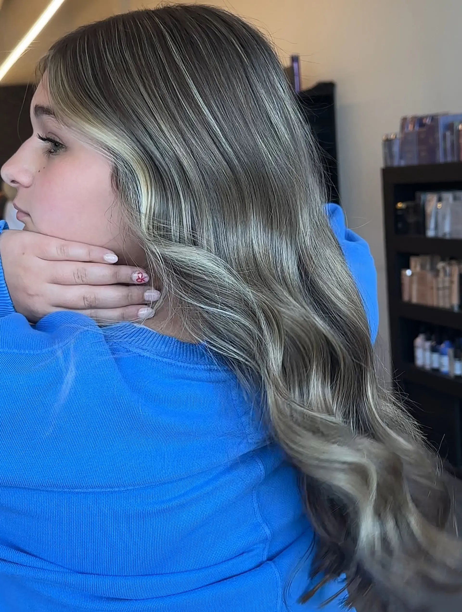 Long ash blonde hair styled in soft flowing waves, featuring fine babylights and brighter face-framing pieces over a natural light brown base. 1