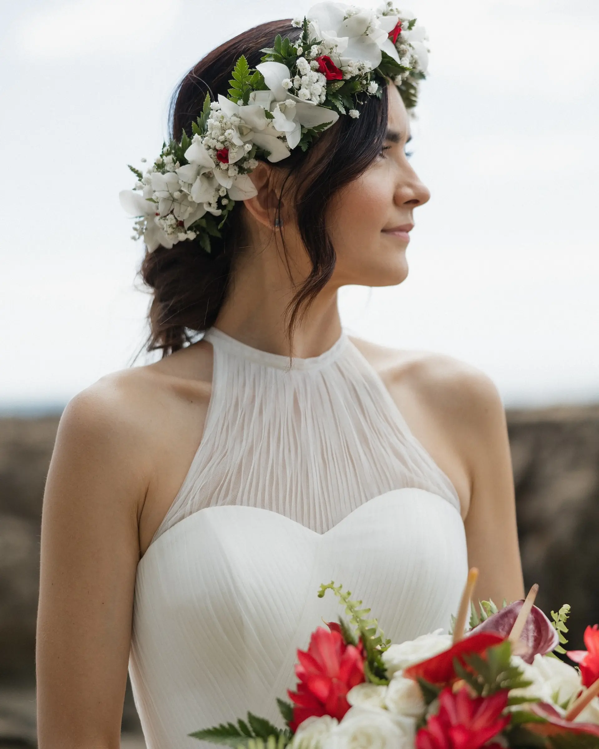 A romantic bridal updo paired with delicate face-framing wavy tendrils and a lush floral crown. 1