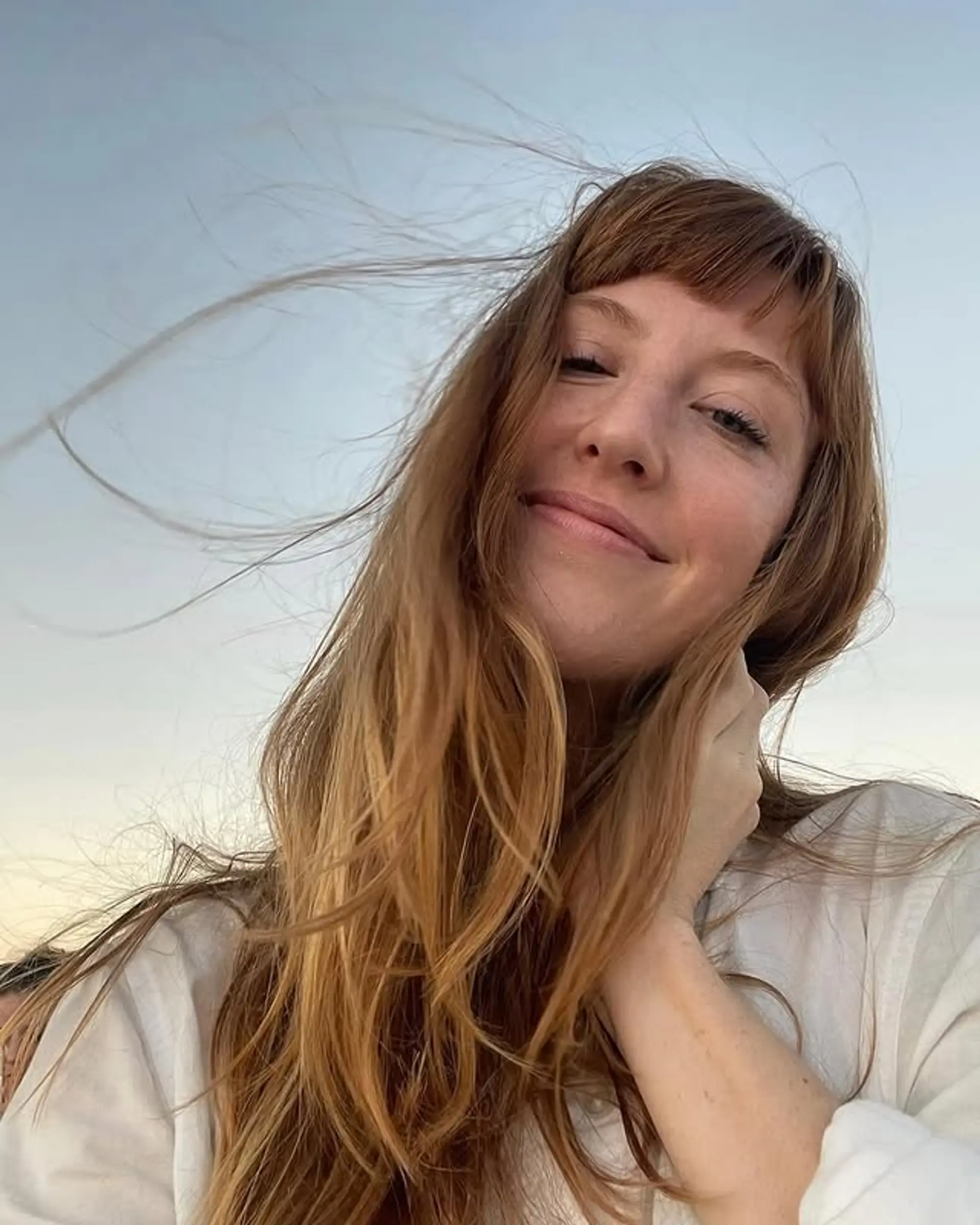 Long, wavy auburn hair with Bardot bangs and face-framing layers. 1