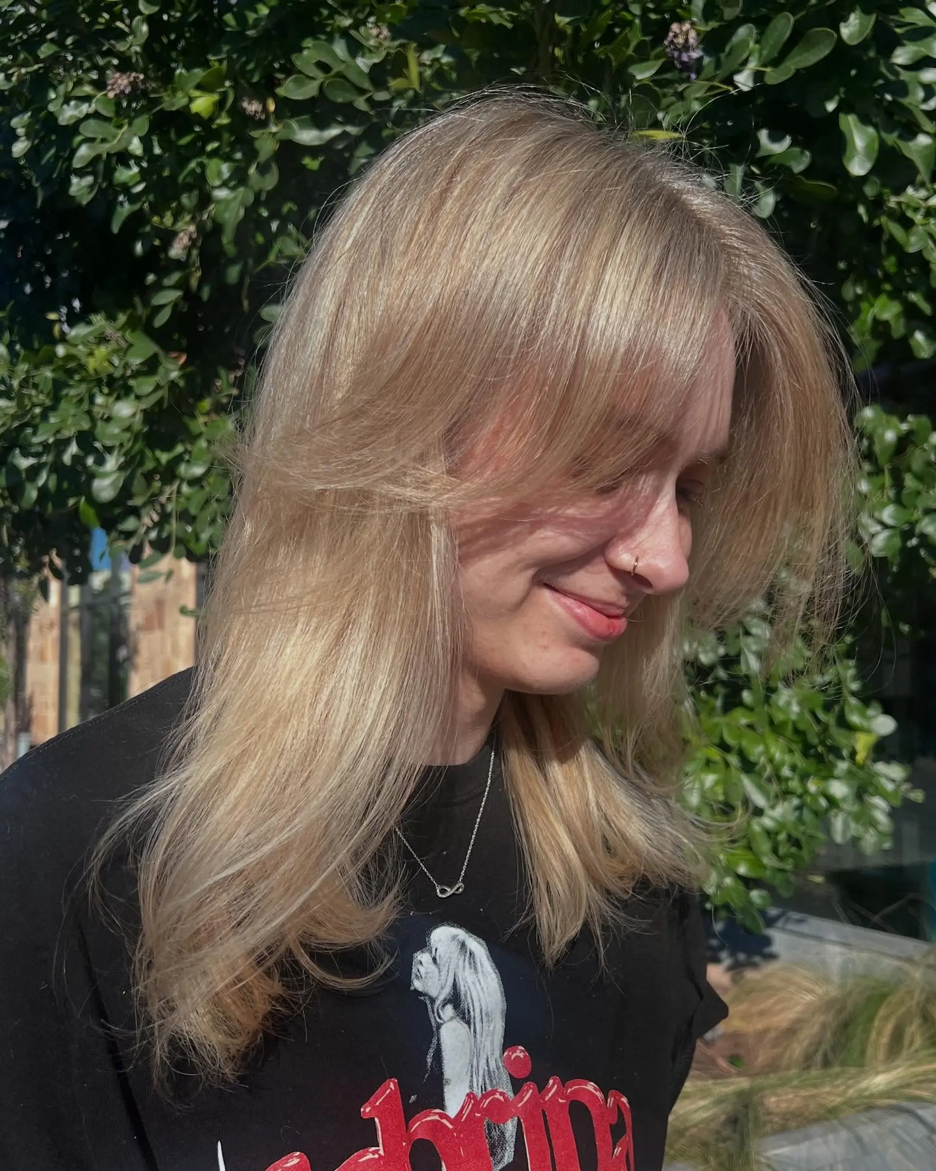 Warm butter blonde hair cut into soft, face-framing layers with curtain bangs and blown-out curved ends. 1