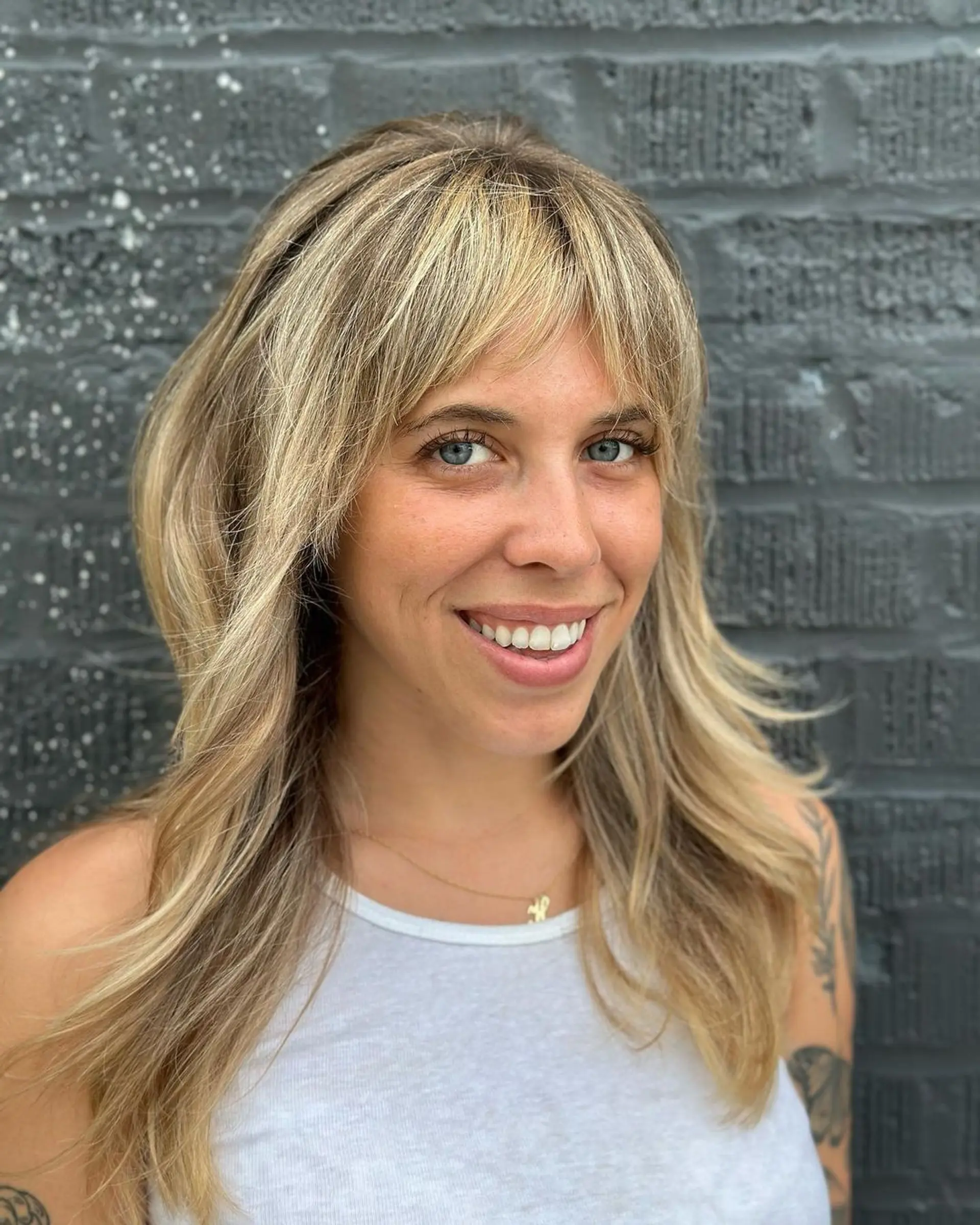 Long wavy blonde hair with multi-tonal highlights, curtain bangs, and a layered cut. 2