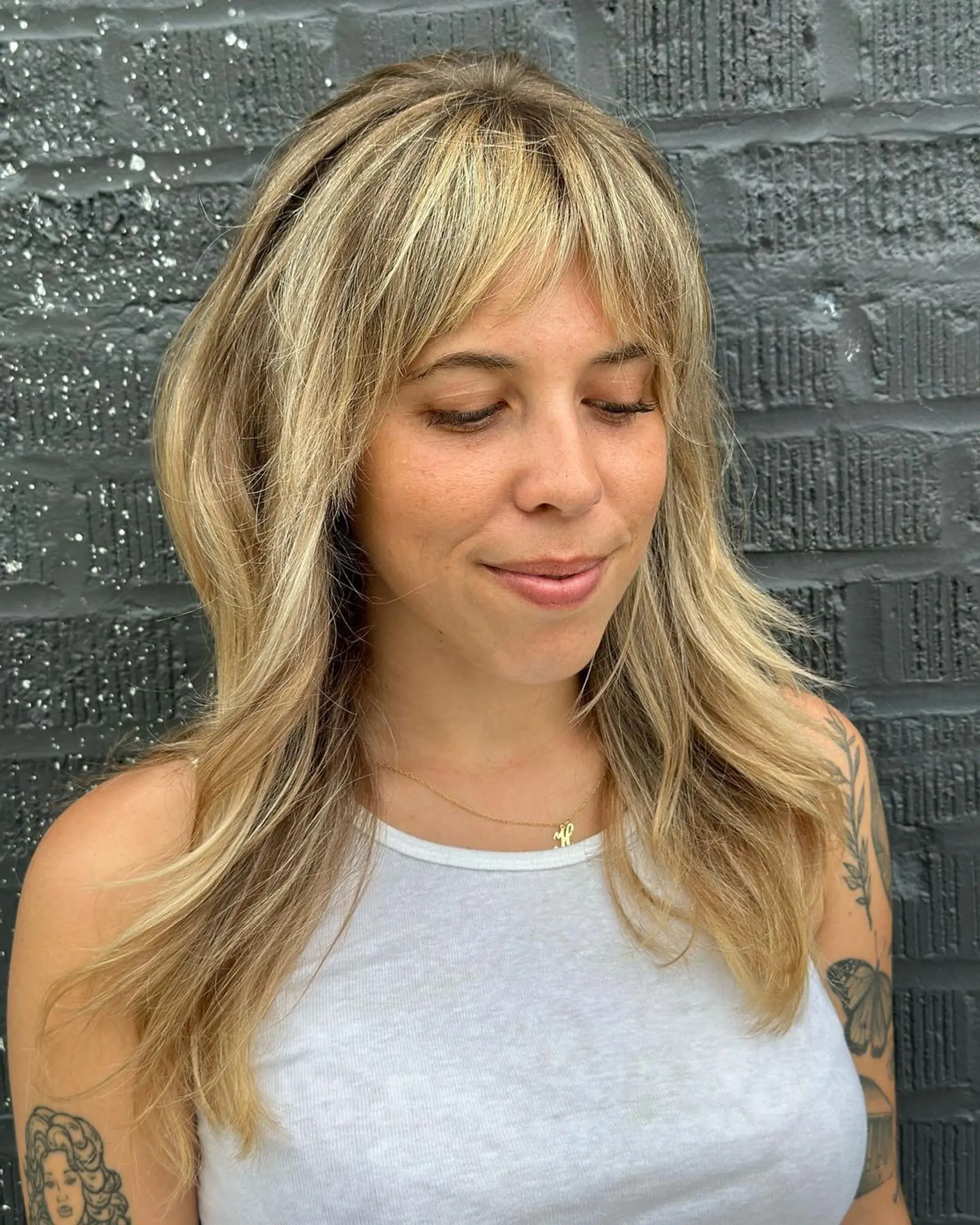 Long wavy blonde hair with multi-tonal highlights, curtain bangs, and a layered cut. 1