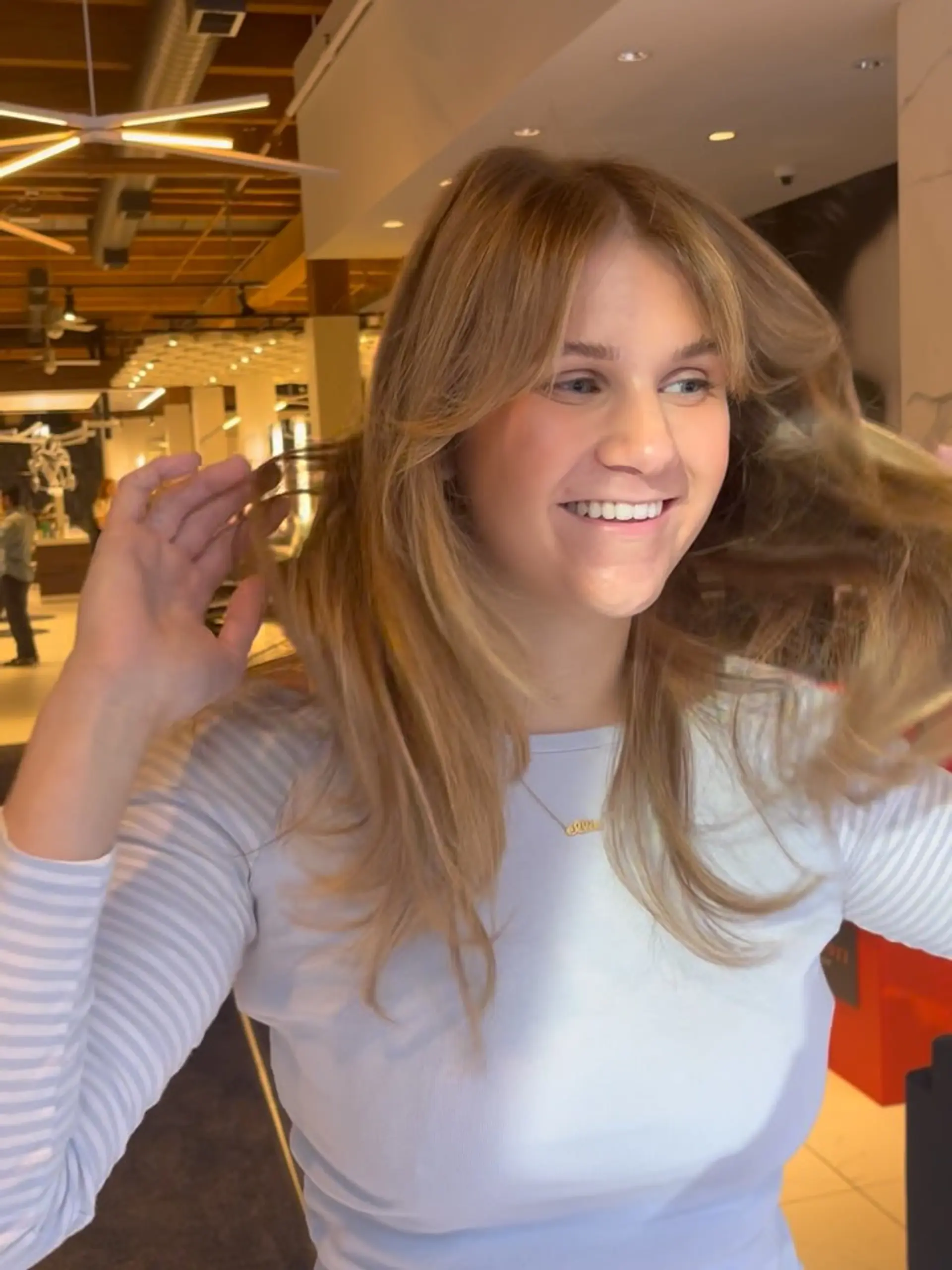 Long warm blonde hair cut with face-framing curtain bangs and soft, voluminous layers styled in an airy blowout. 1