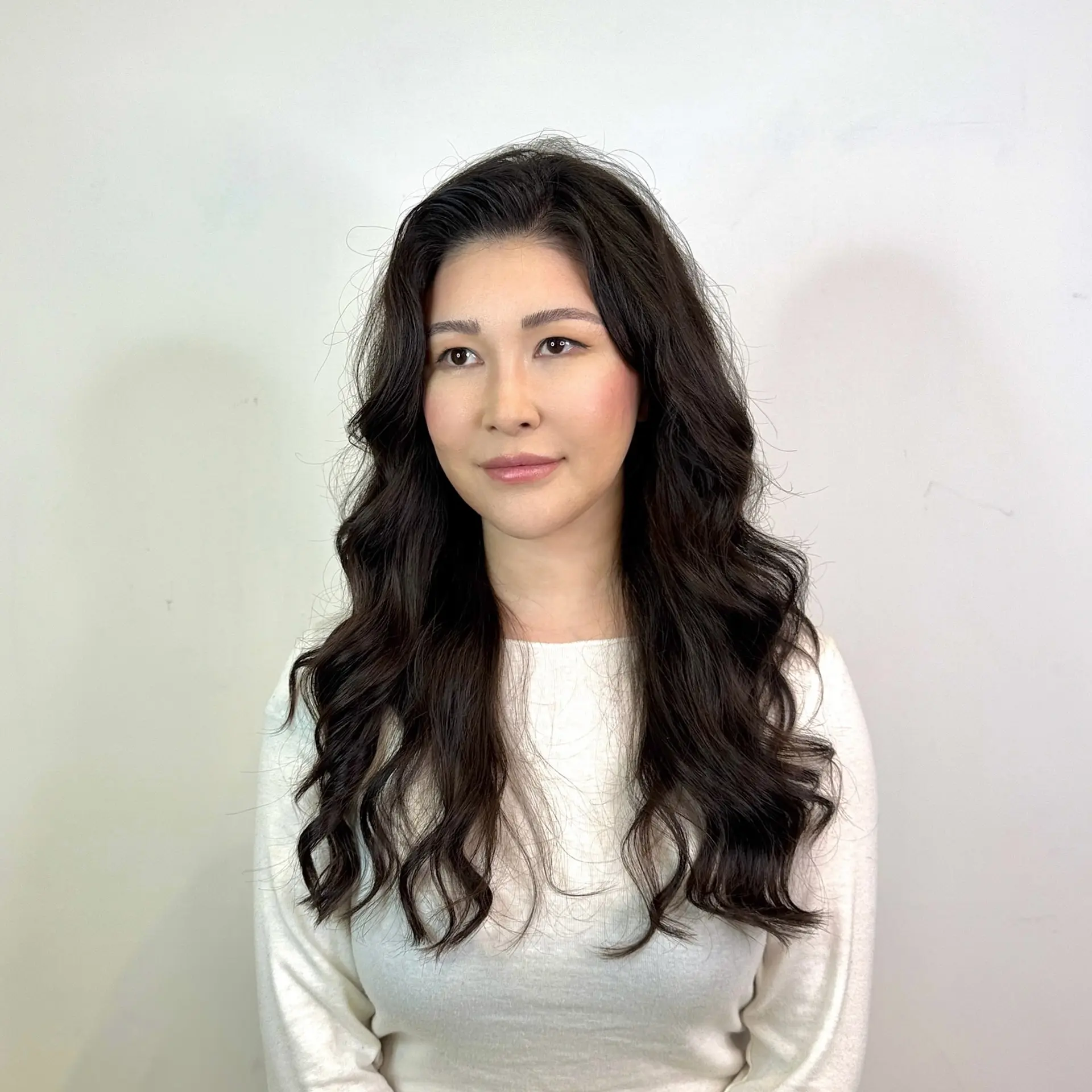 Long, flowing dark hair styled into soft, voluminous loose waves with a center part. 1
