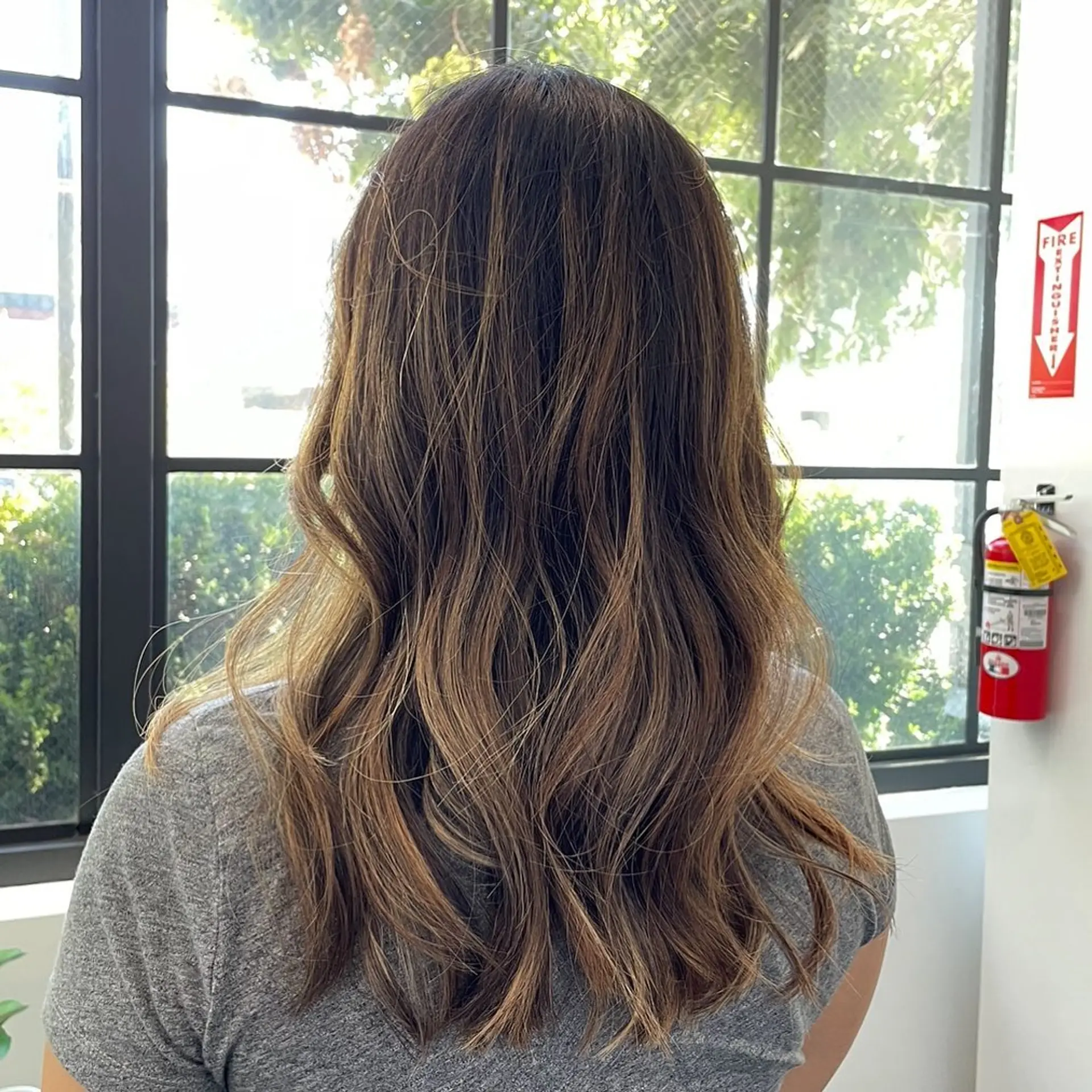 Long hair cut with textured layers and styled in soft, loose waves featuring dimensional caramel balayage. 1