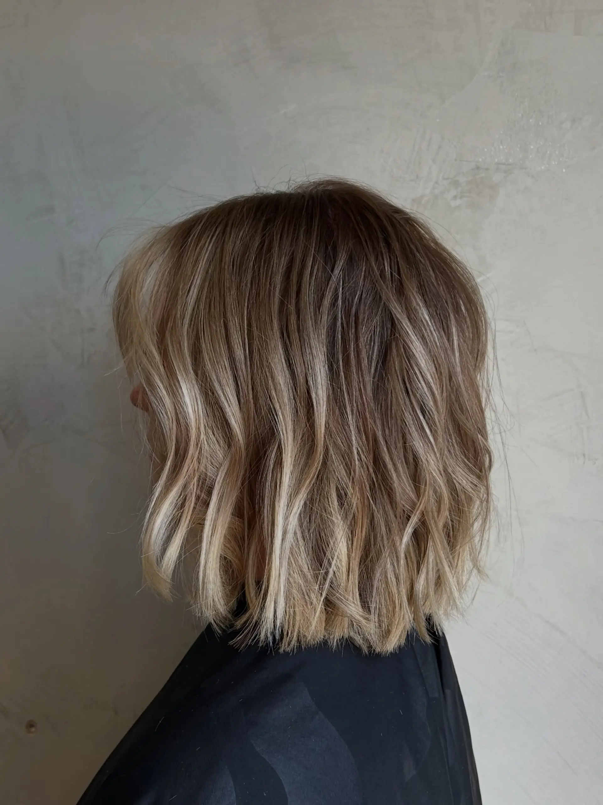 A blunt, textured shoulder-length bob styled with subtle bends and loose waves. 1