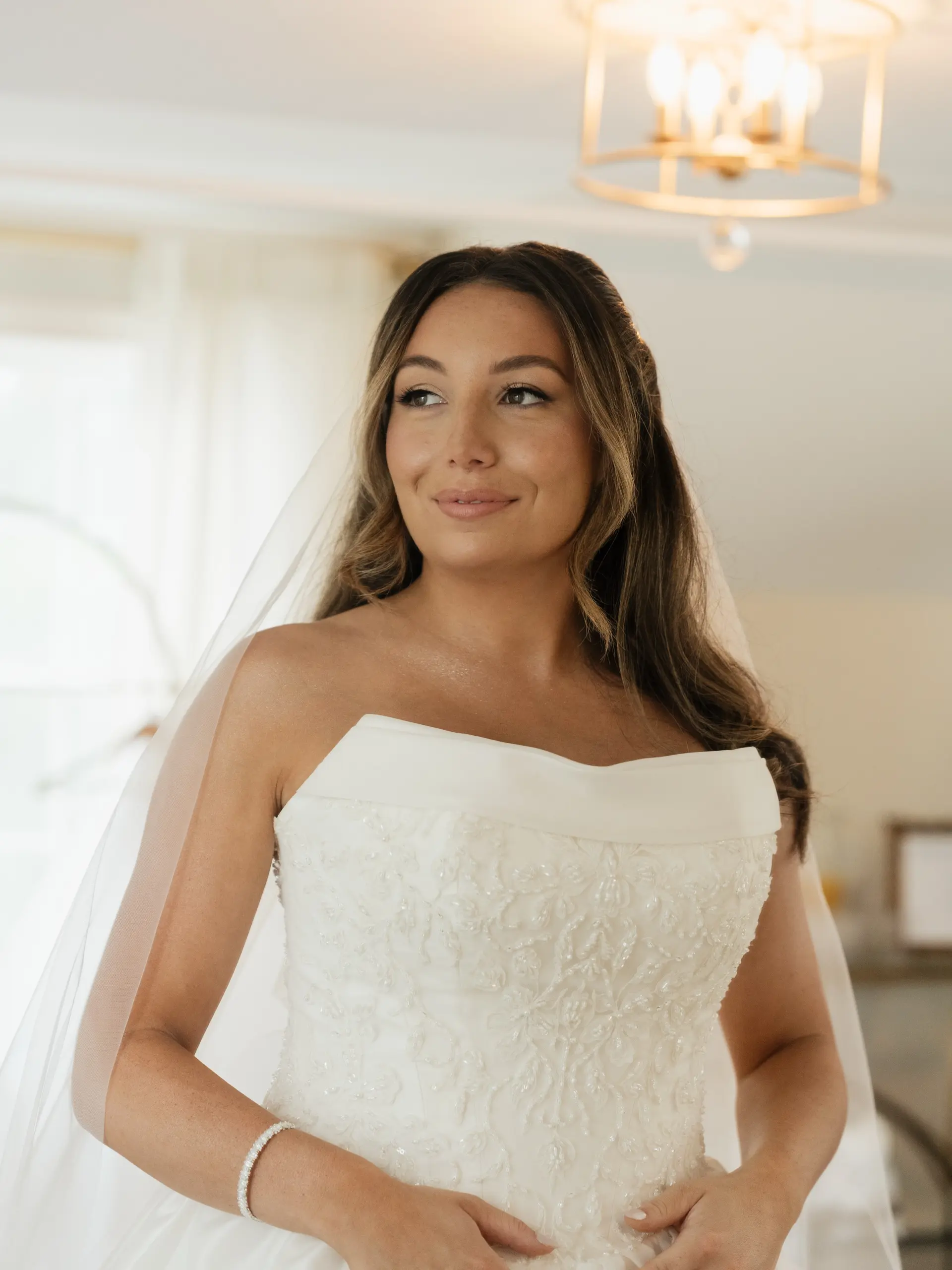 A timeless bridal style featuring soft, cascading waves parted down the middle and paired with a veil. 1