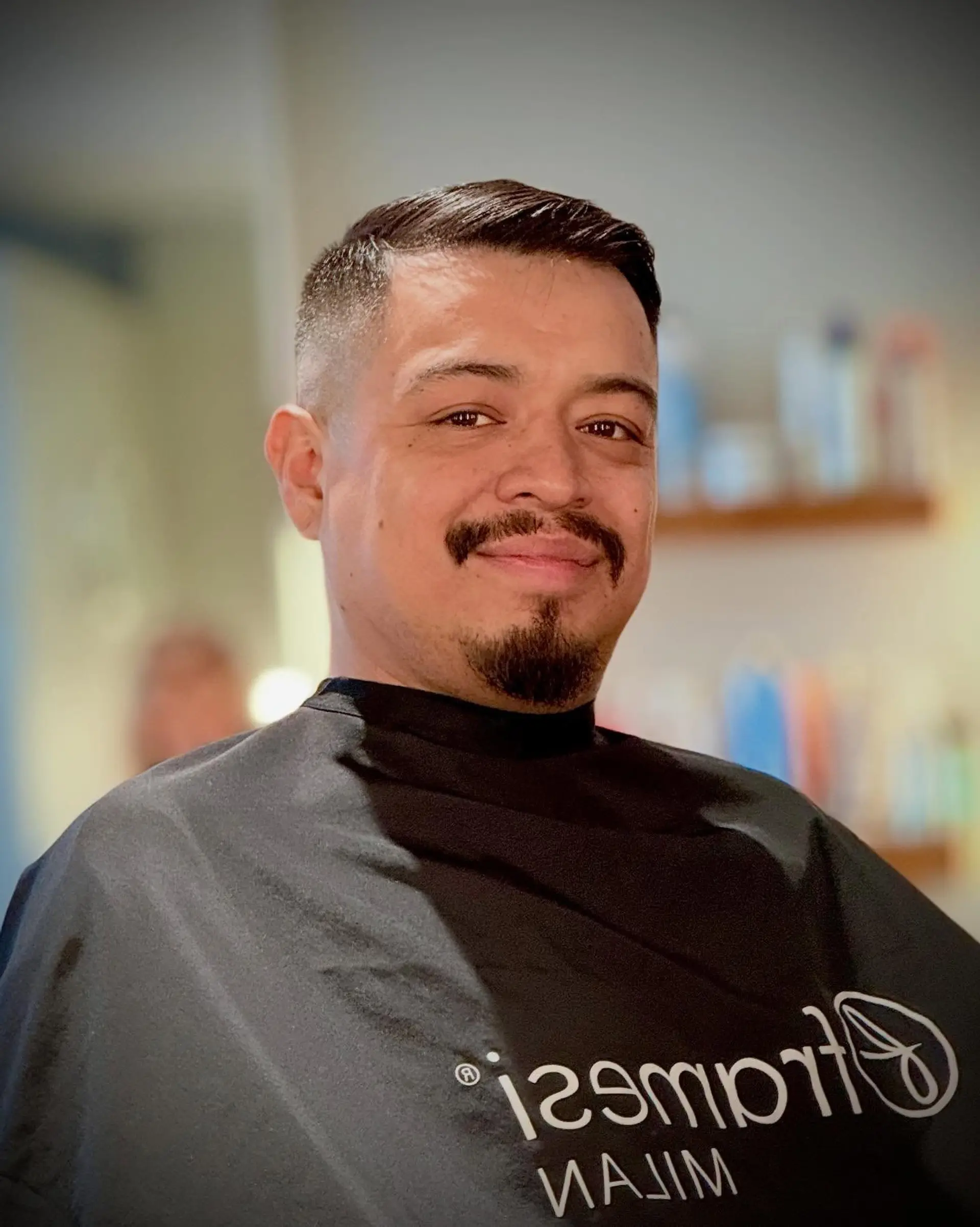 A clean high and tight fade with short, neatly styled hair on top paired with groomed facial hair. 1