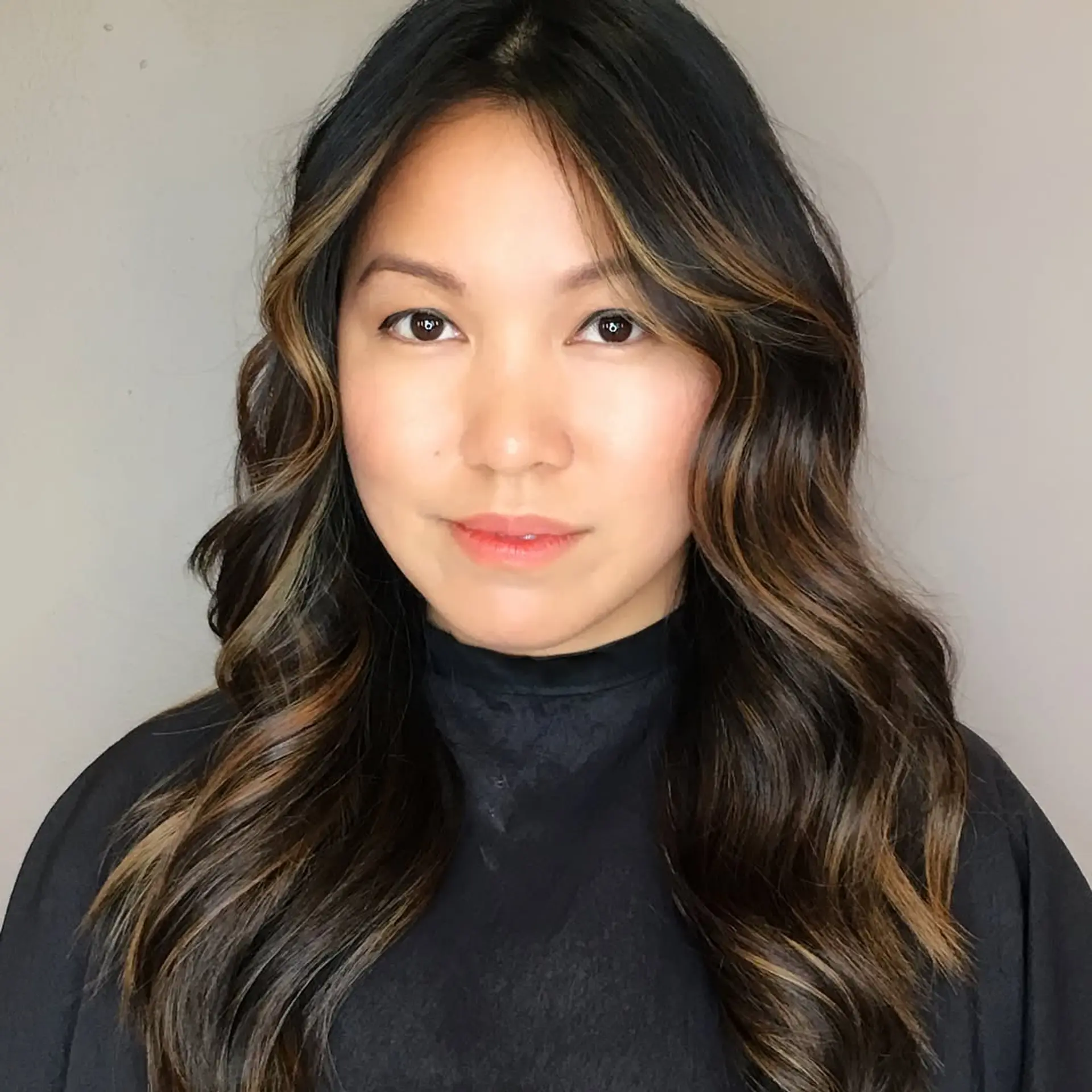 Long dark brunette hair styled with subtle caramel balayage and soft, voluminous waves. 1