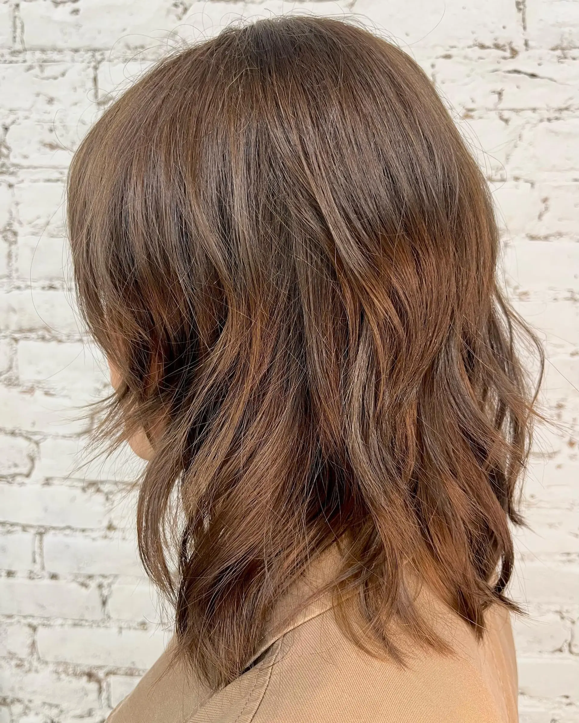 Medium-length textured layered cut styled with soft waves in a rich warm brown tone. 1