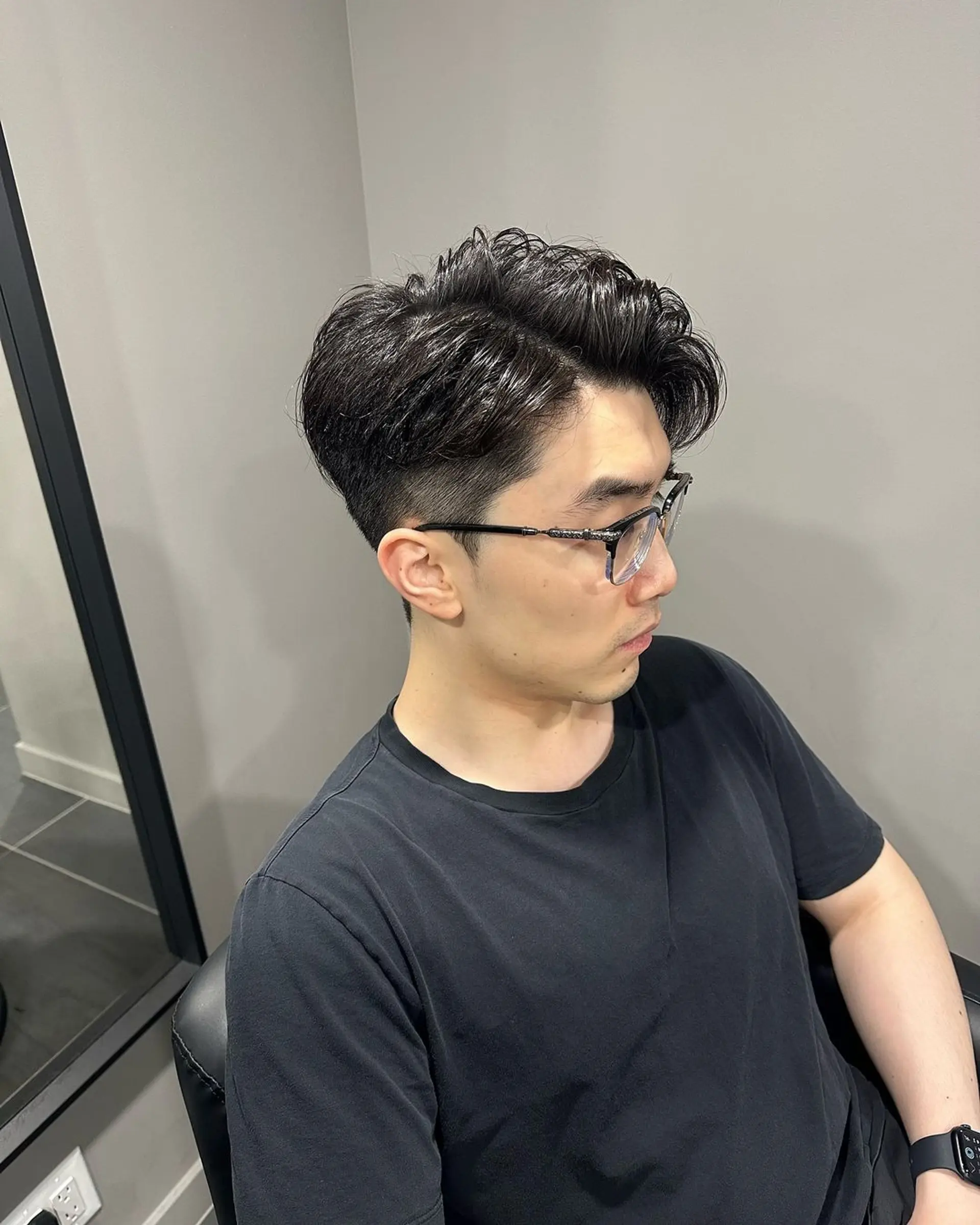 A 'Modern Tapered Pompadour' with an undercut back and sides, voluminous wavy top swept to the side, in black. 2