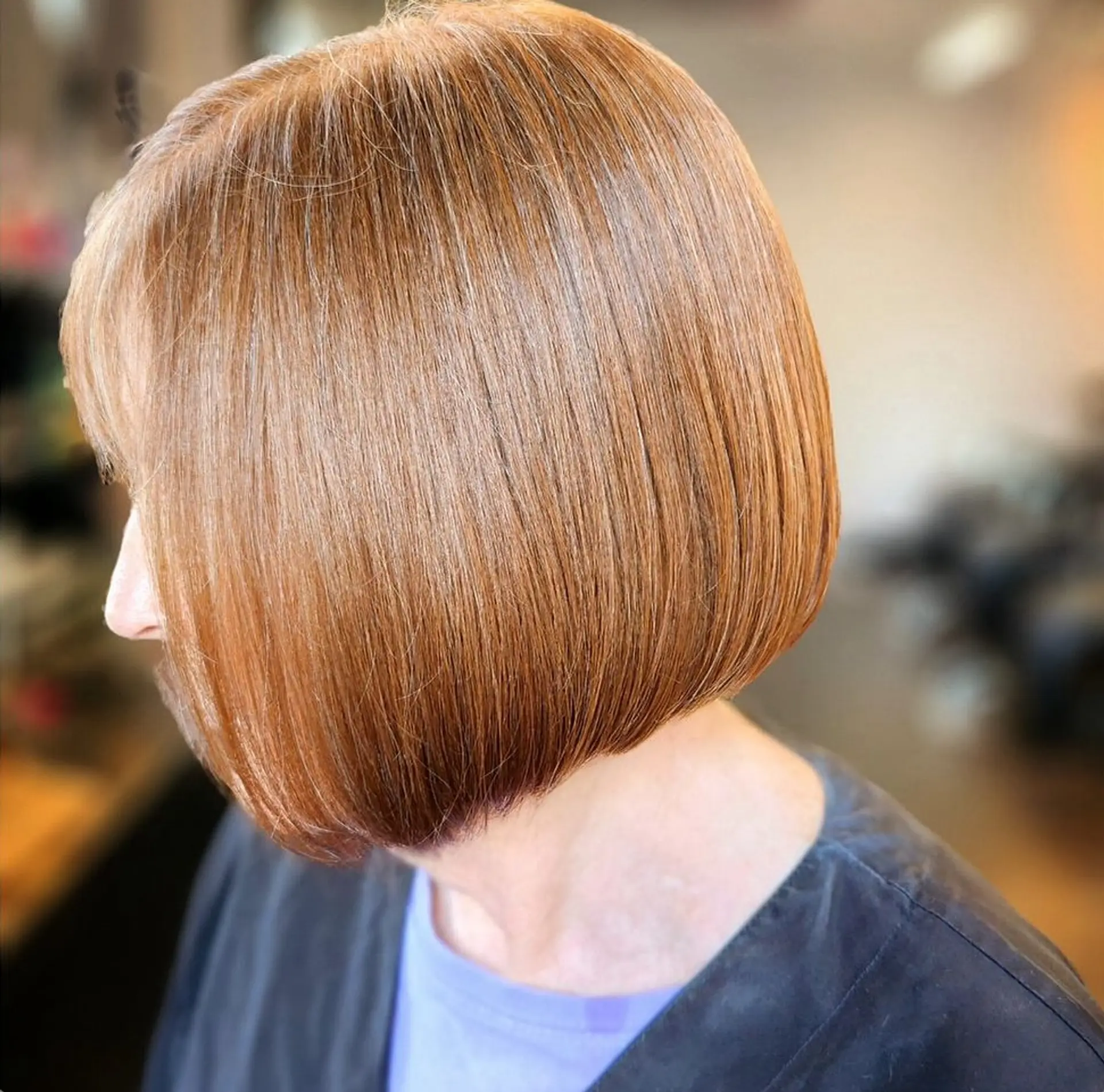 A sleek, chin-length golden copper bob haircut with soft fringe and curved ends. 1