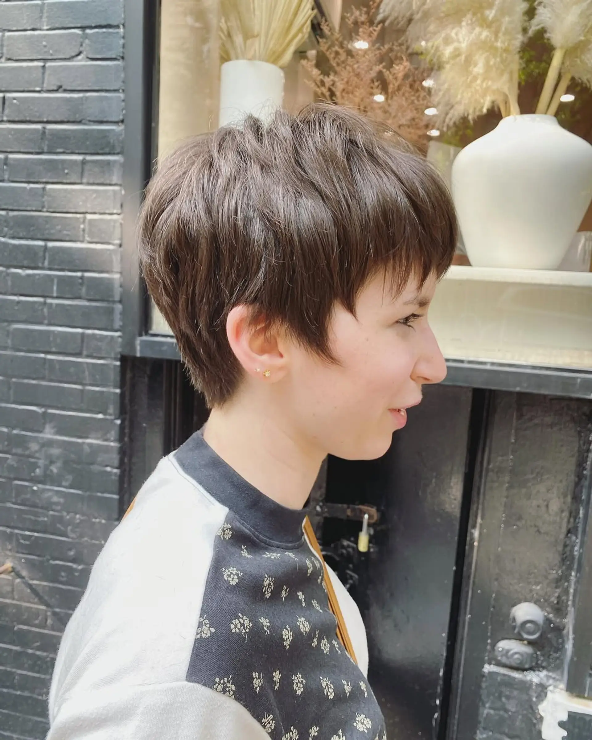 A short, textured pixie cut with choppy layers and fringe bangs in straight brown hair. 3