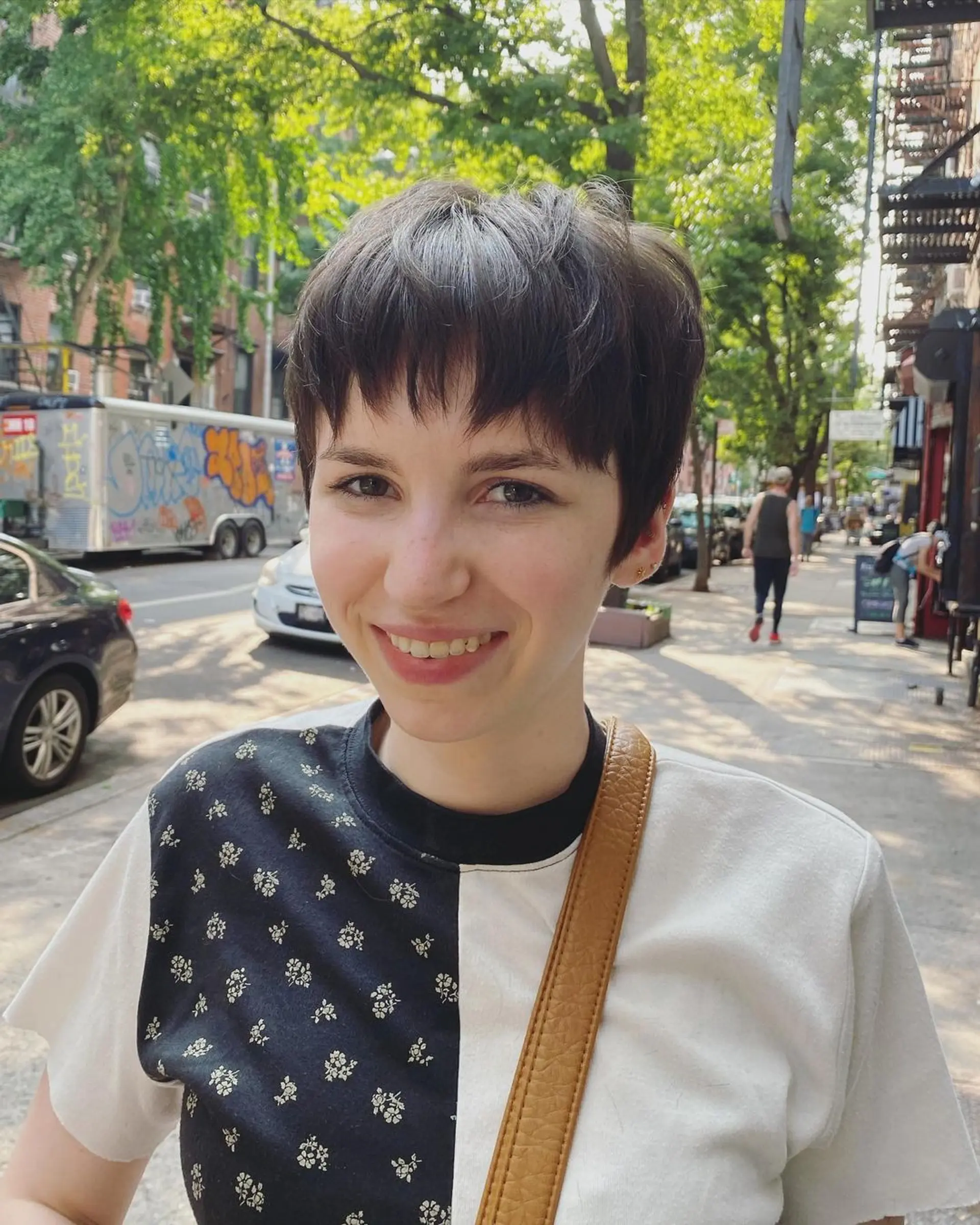 A short, textured pixie cut with choppy layers and fringe bangs in straight brown hair. 2