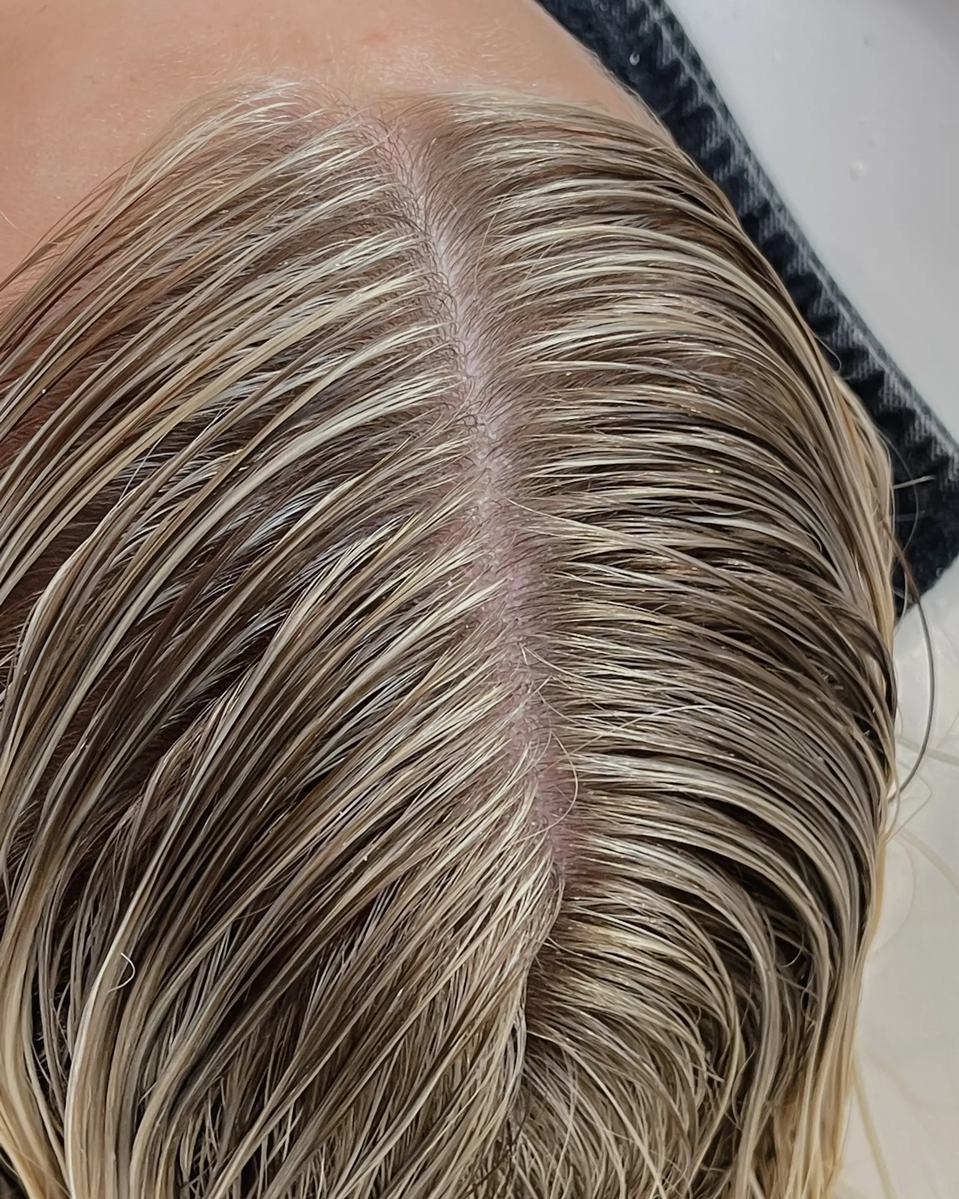 Close-up view of ultra-fine, seamless blonde babylights blended precisely to the root along a clean part. 1