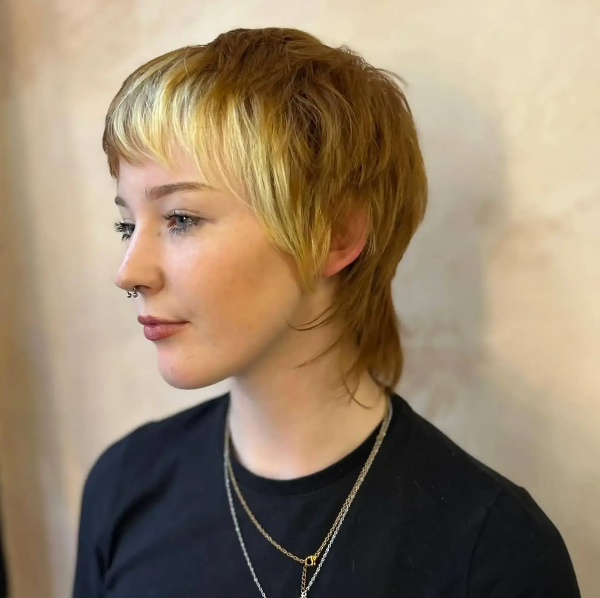 An edgy blonde mullet with short layers, choppy fringe, and a two-tone color scheme that blends blonde and brown.