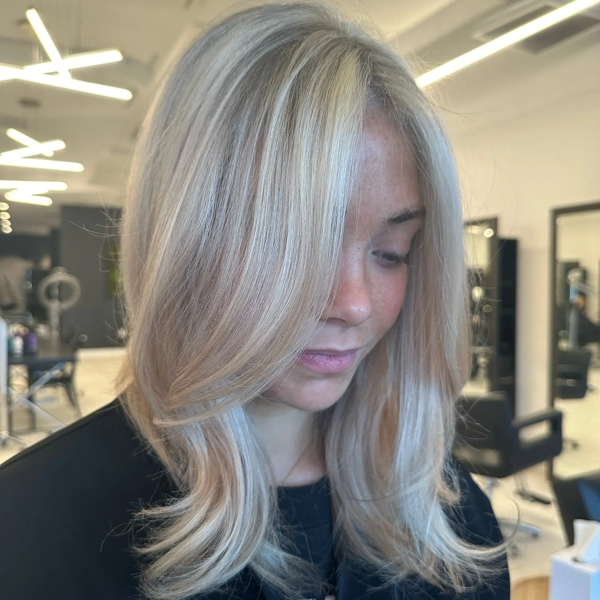 Medium-length bright blonde hair styled in a smooth blowout with soft face-framing layers. 1