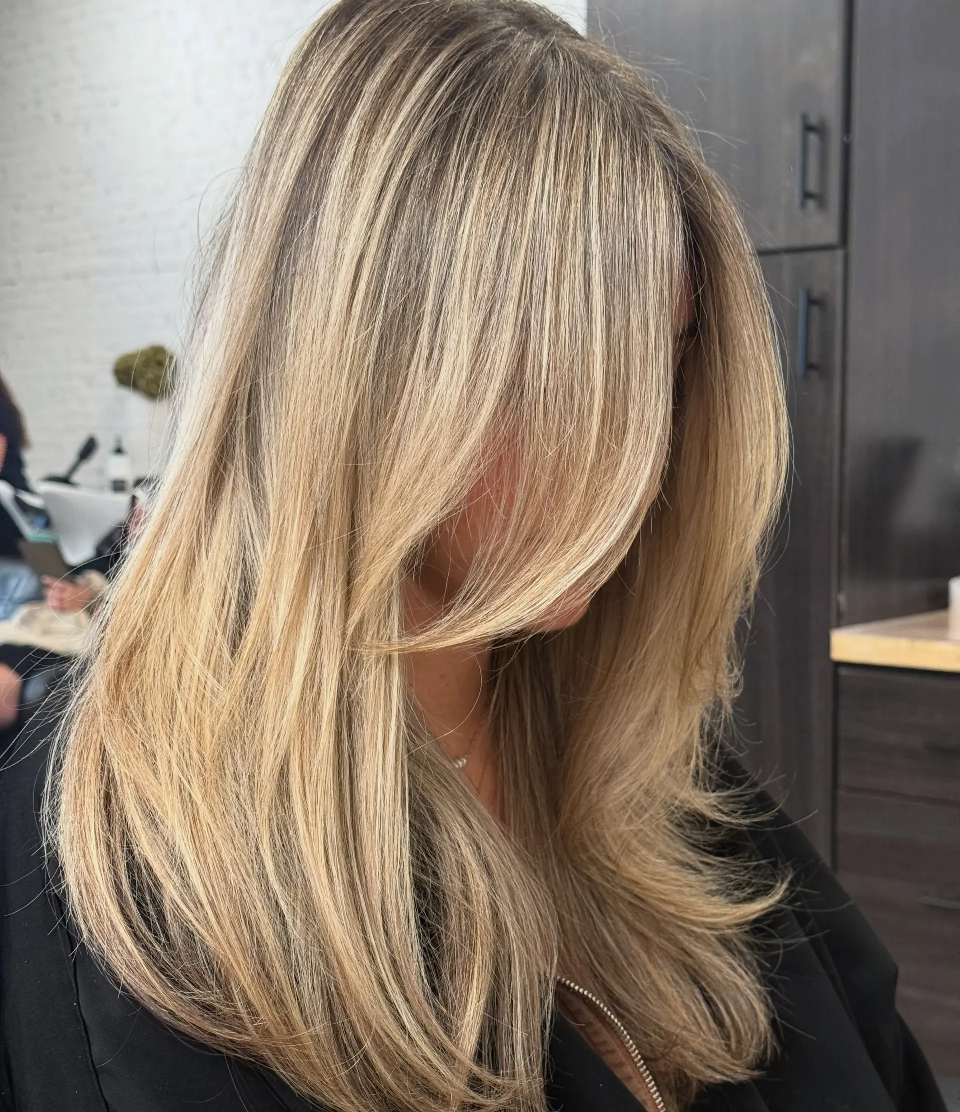 Long multi-tonal blonde hair cut with blended layers and sweeping face-framing fringe. 1