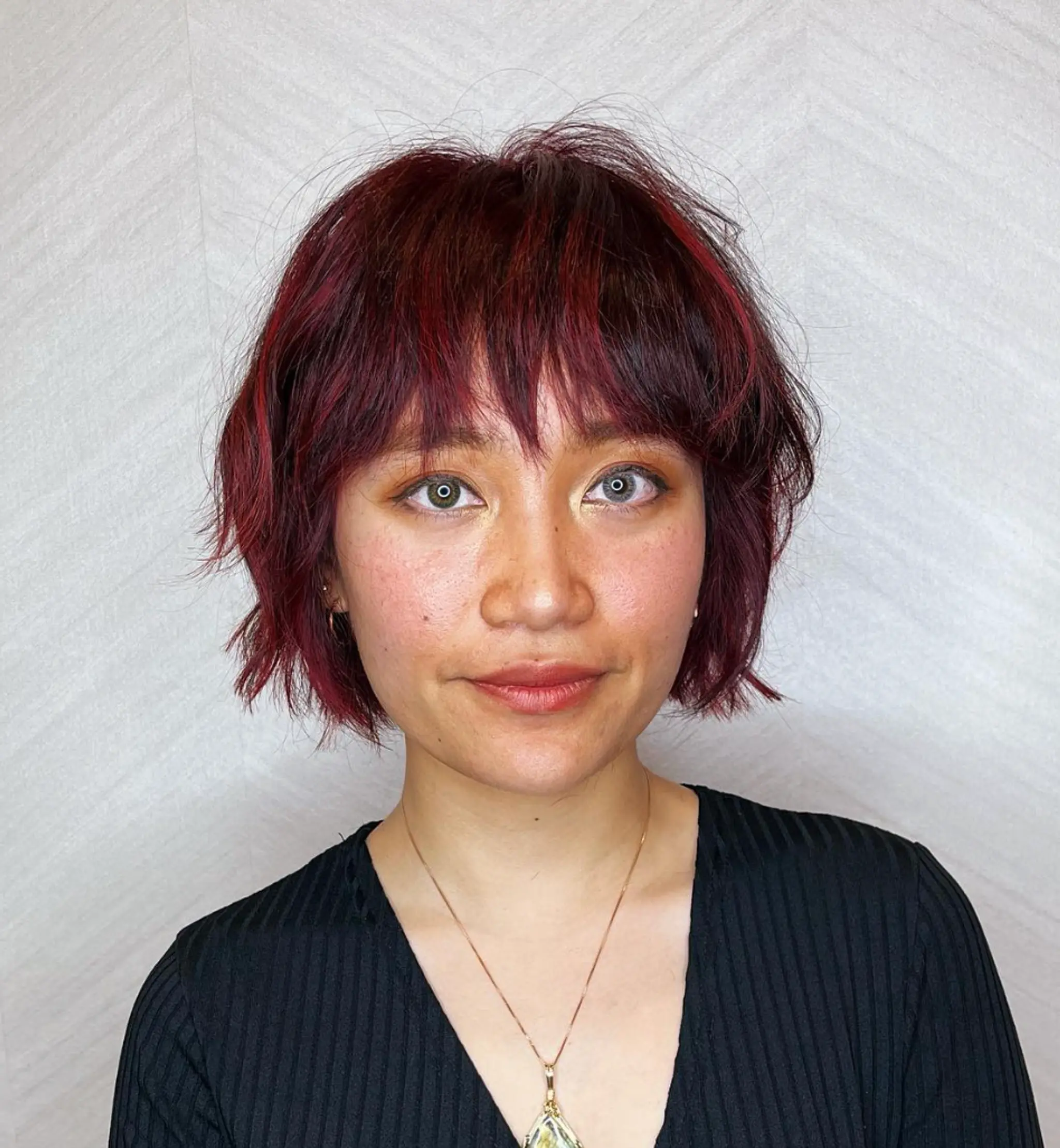 A short, wavy cut with burgundy and crimson hues, featuring textured ends, a tousled finish, face-framing fringe, and layered elements.

Cut and style by @juliamannino_hair

