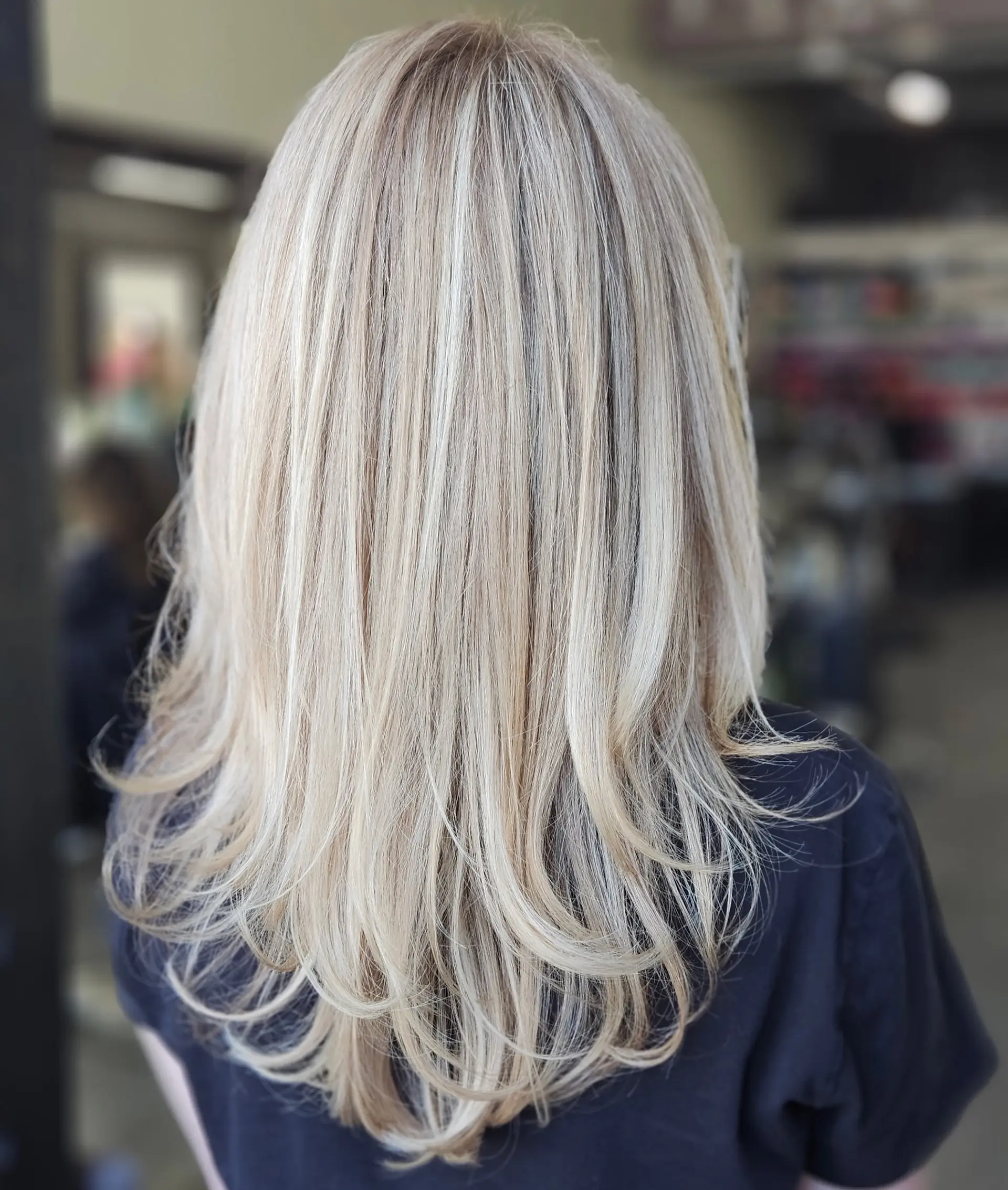Medium-to-long straight blonde hair featuring finely blended cool-toned highlights and a soft under-curled blowout. 1