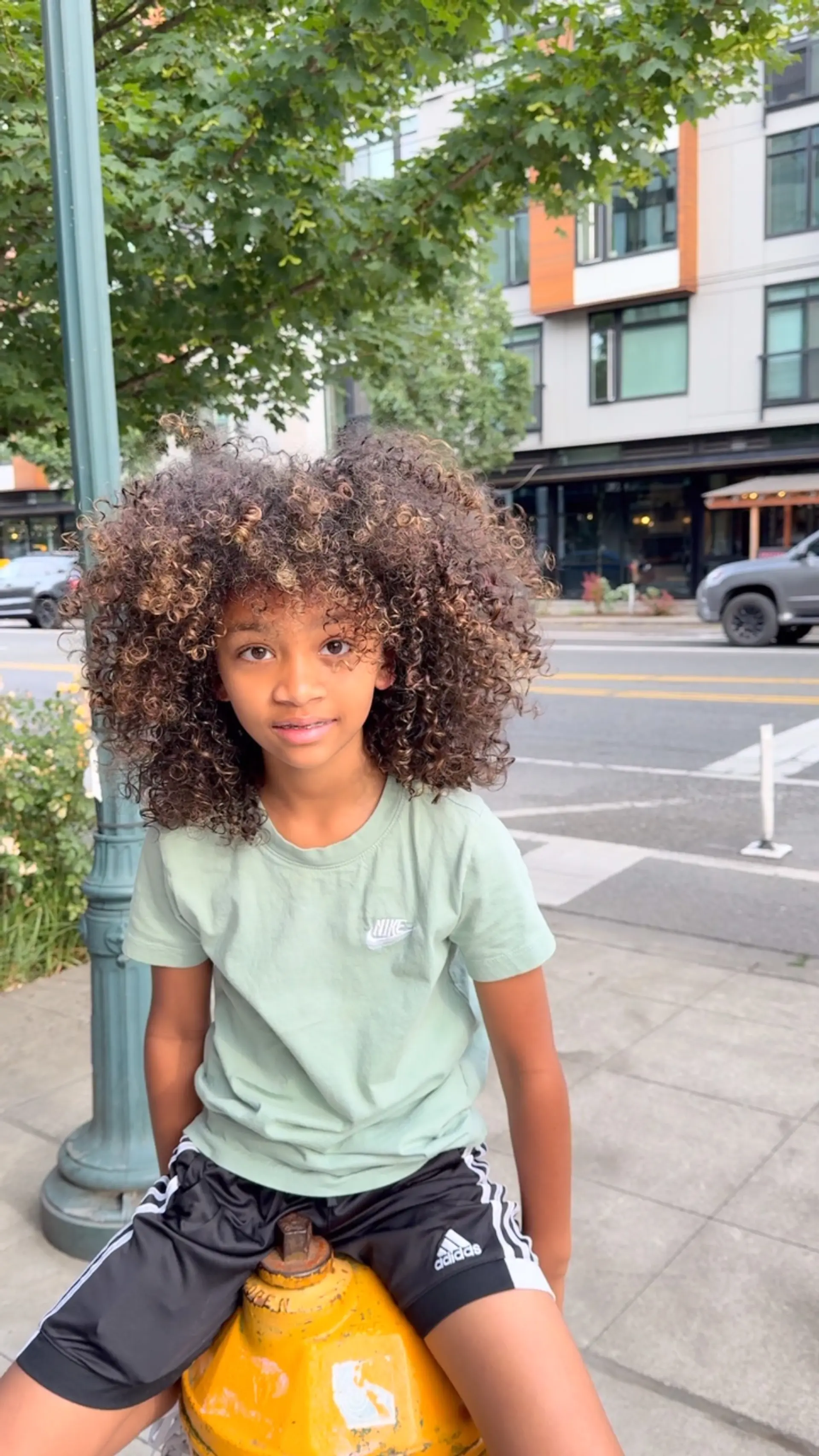 Shoulder-length, high-volume natural curls with defined spiral texture and warm caramel highlights. 1