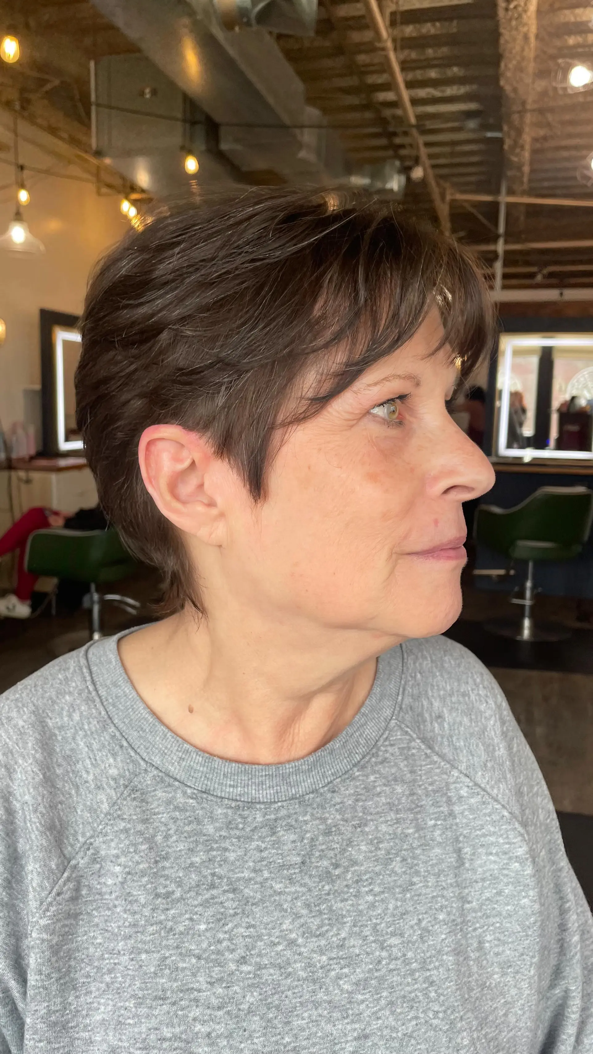 A textured short pixie haircut with soft brow-skimming fringe and cleanly tapered sides. 1