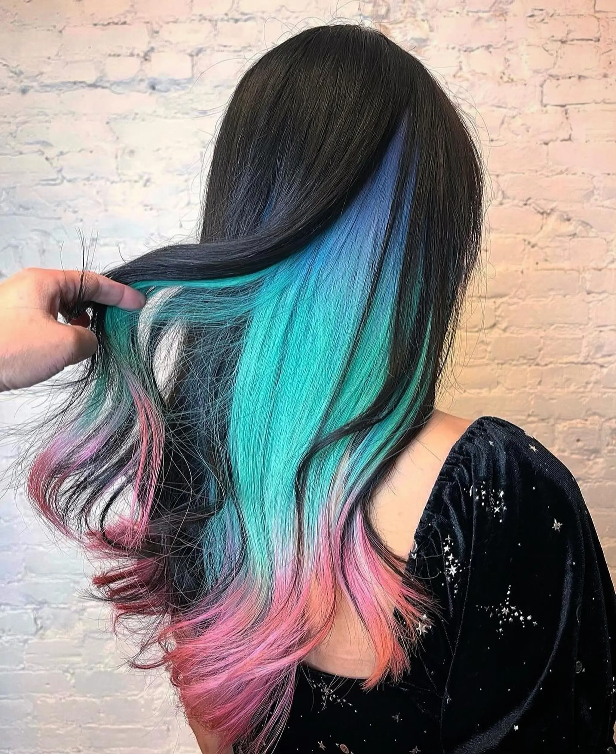 Long, straight hairstyle with a vibrant multicolored ombre transitioning from black to blue, turquoise, and pink. Smooth layers accentuate the gradient blend, offering a bold and playful look.