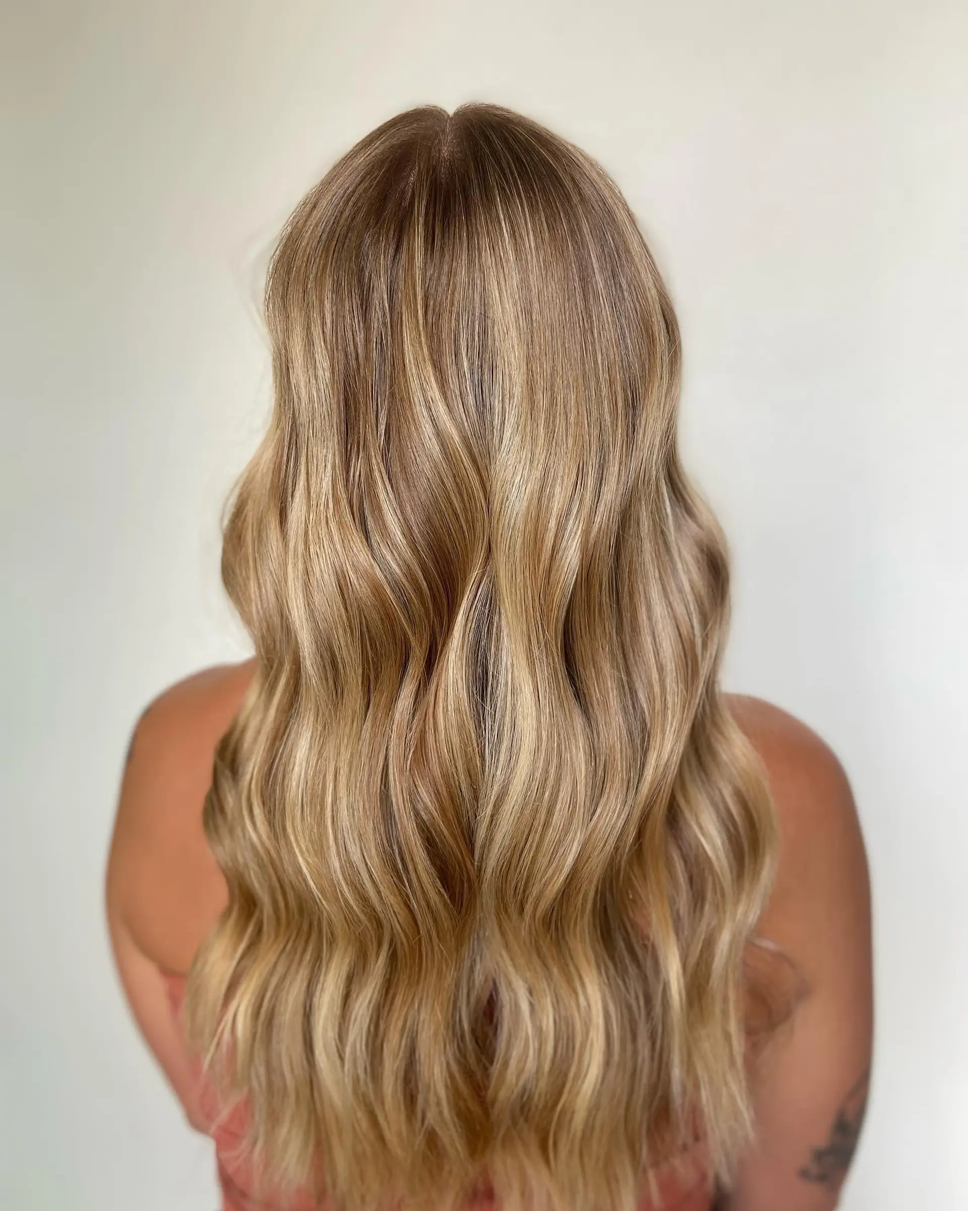 Long golden blonde hair styled in soft, cascading waves with seamless multi-dimensional highlights. 1