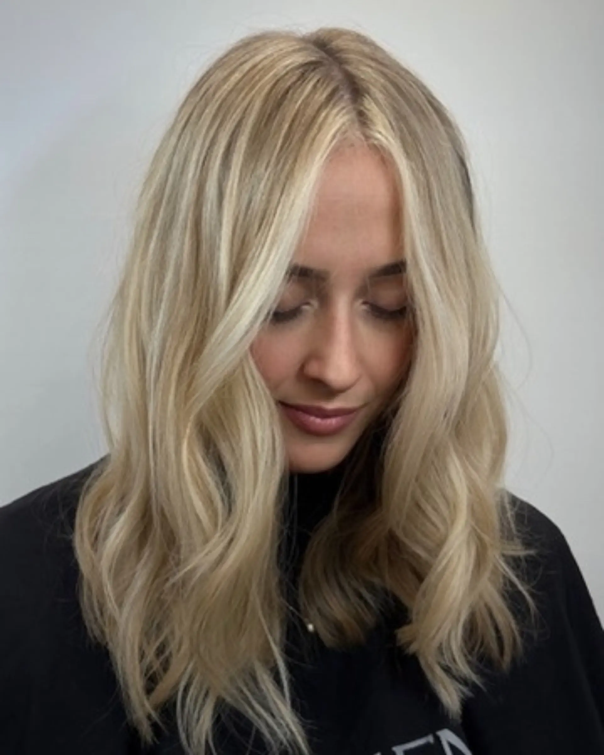 Medium-length bright blonde hair styled with soft, loose waves and bright face-framing highlights. 1