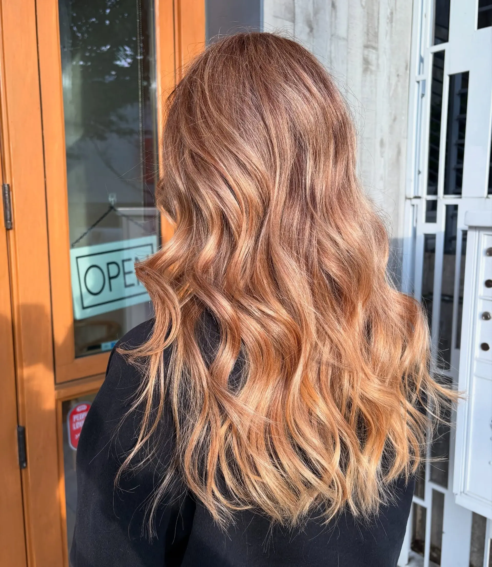 Long strawberry blonde hair styled with soft, loose waves showing dimensional copper and blonde tones. 1