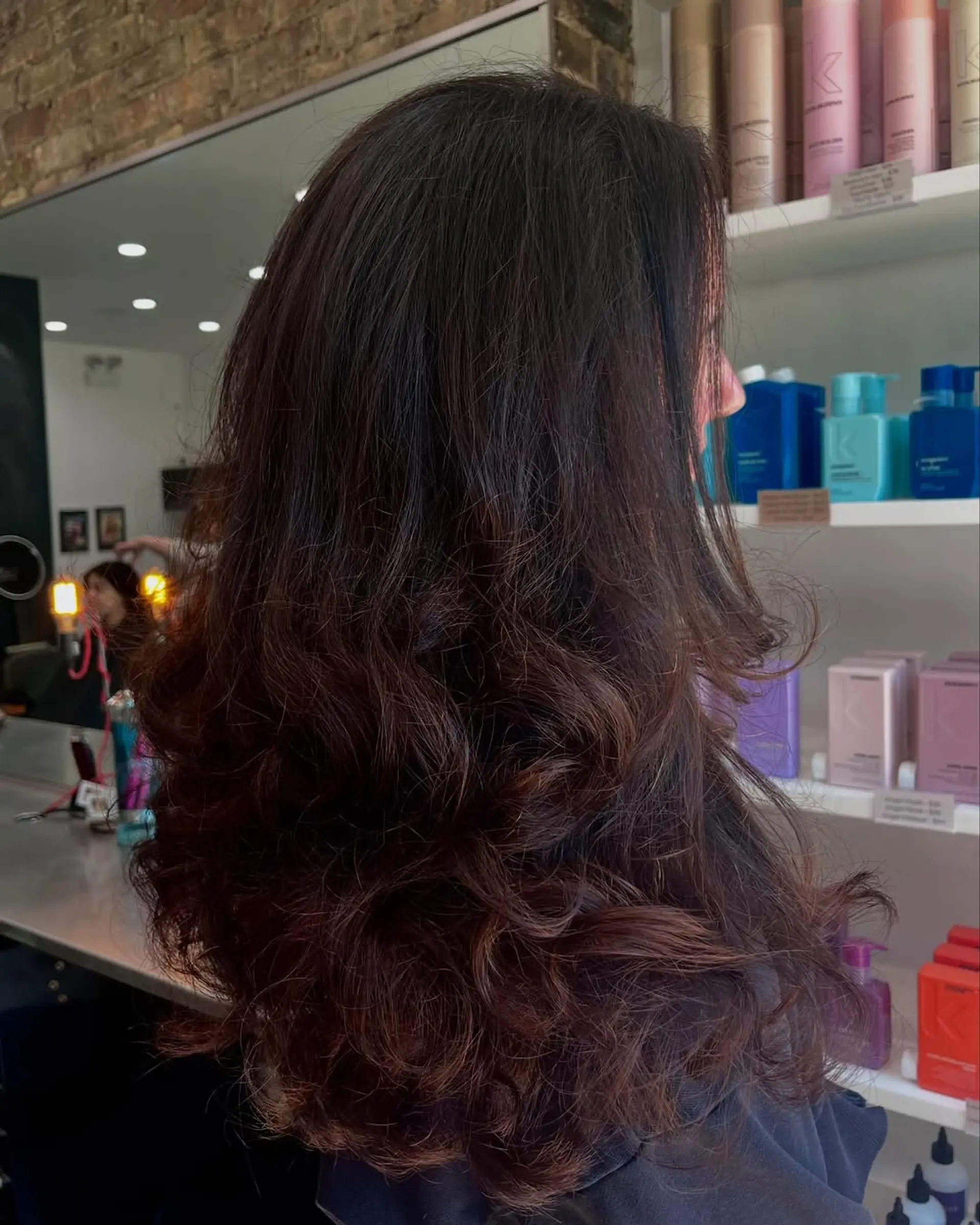 A long layered haircut with significant volume and bouncy waves, giving the hair a full and dynamic appearance with a soft finish. 1