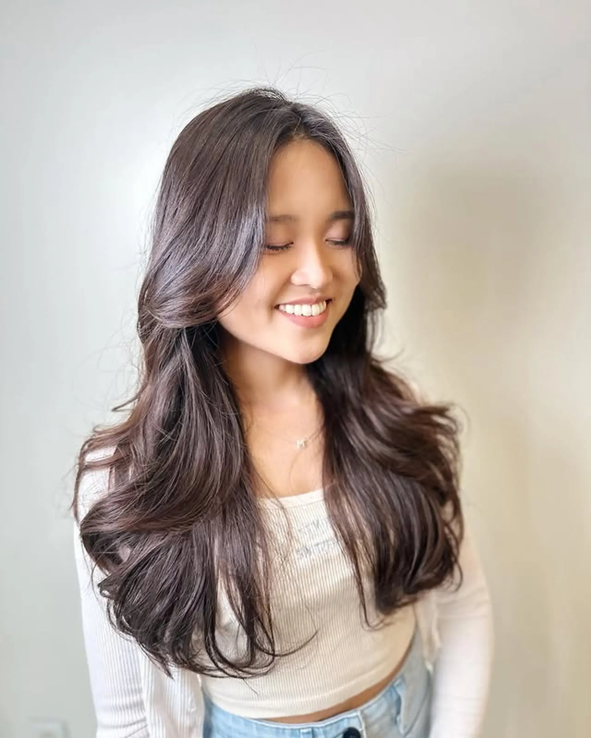 Long layered hair with soft waves and curtain bangs. 1