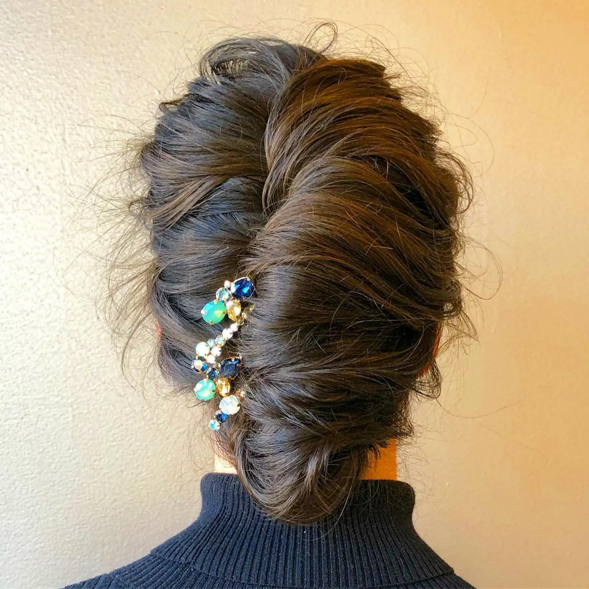 A modern textured French twist updo accented with an ornate jeweled hair accessory. 1