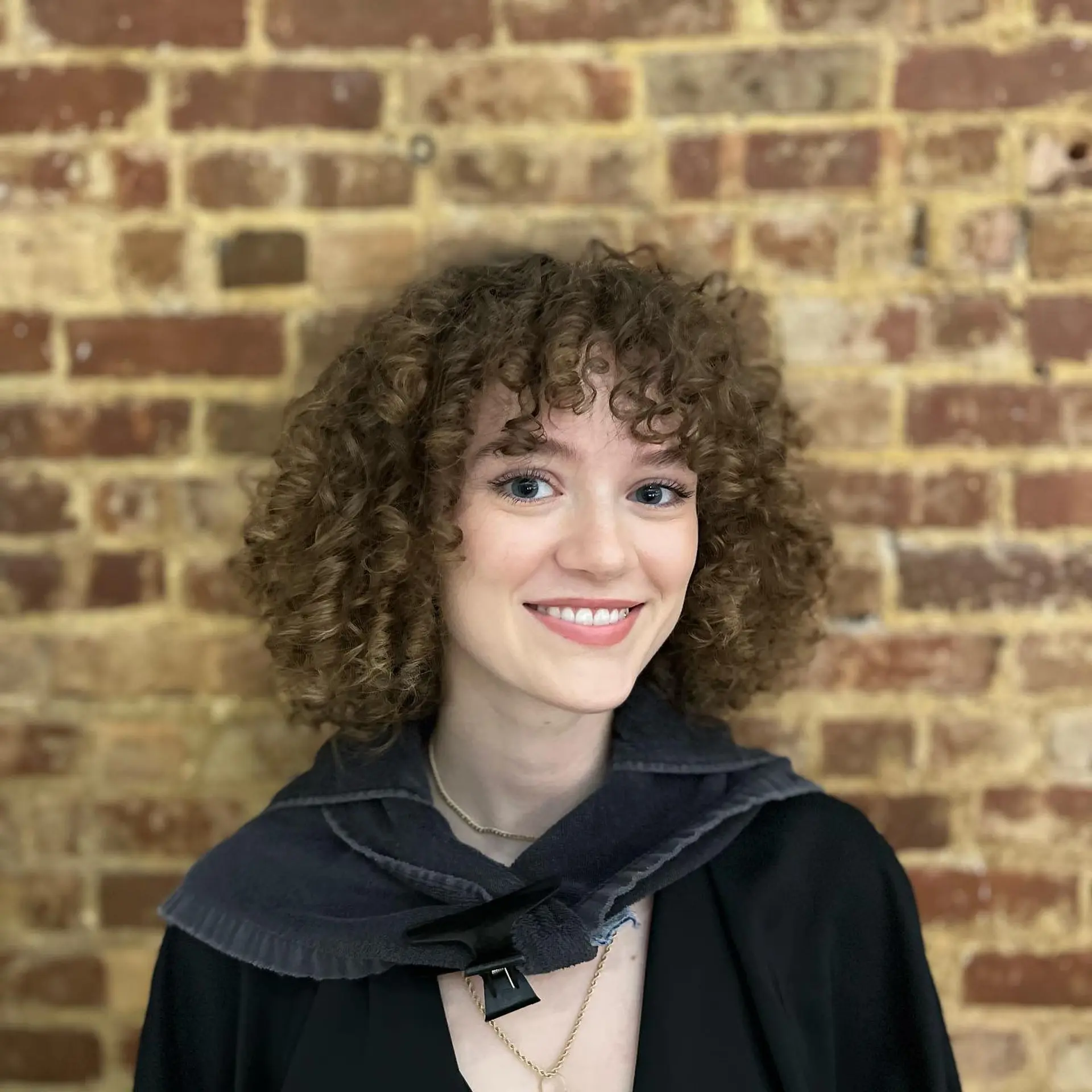 A textured curly shag haircut with full bangs and voluminous curls. 1